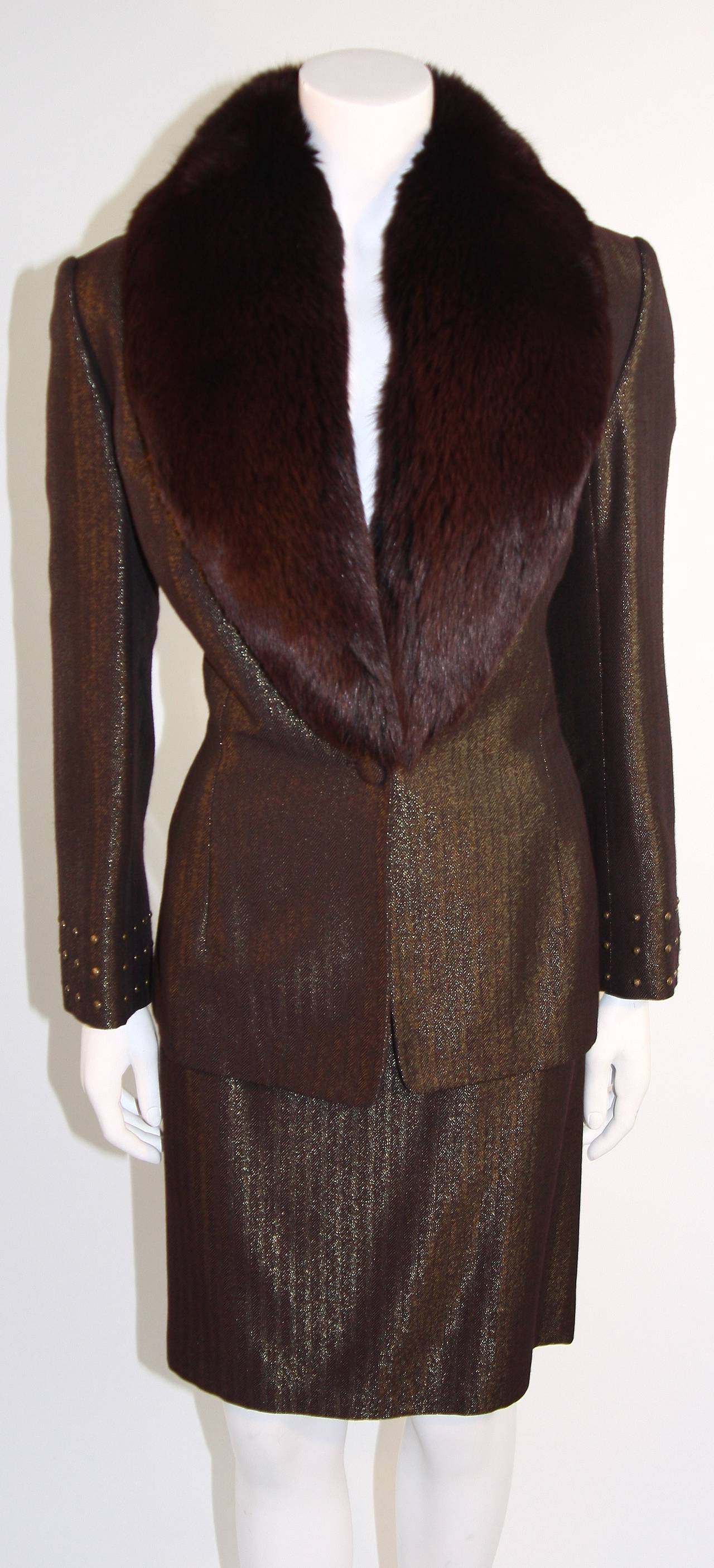 This is a stunning Badgley Mischka suit. The suit is composed of a beautiful burgundy metallic silk and features a detachable fox collar. The jacket has center front button closures and the skirt features a zipper closure. Made in U.S.A.