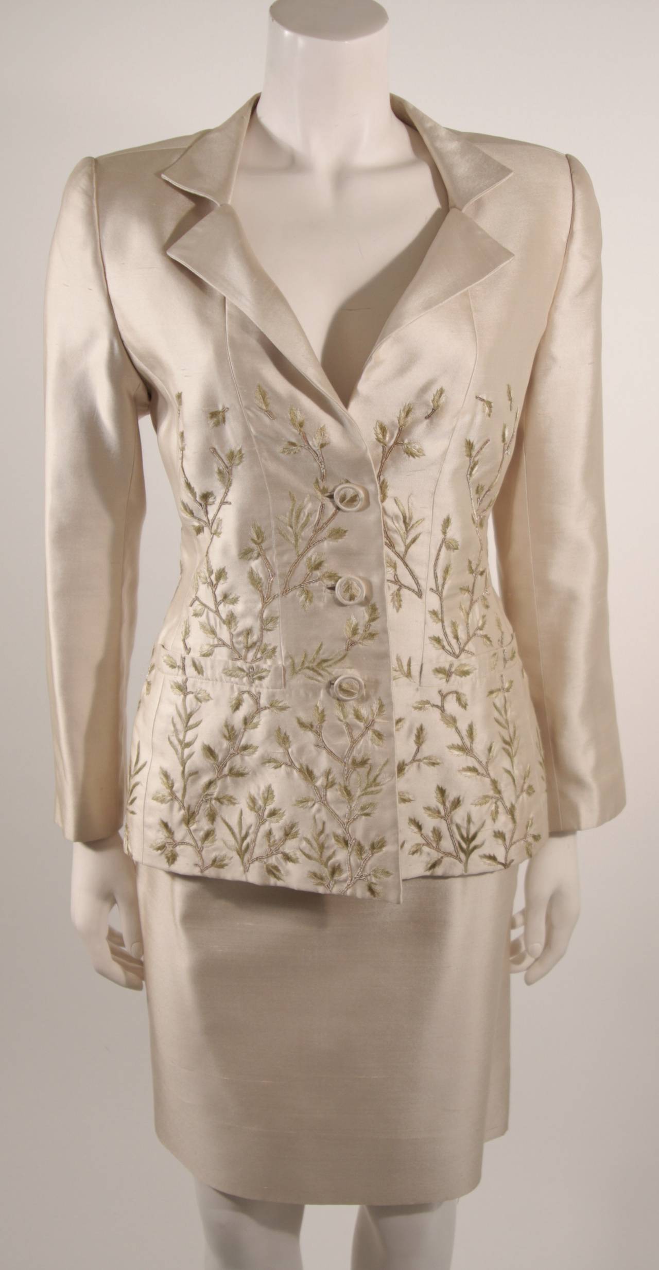 This is a stunning Oscar De La Renta skirt suit. The suit is composed of a champagne hued silk with sage leaf and branch embroidery. The jacket has center front button closures, and the skirt features a  zipper for ease of access. 

Measures