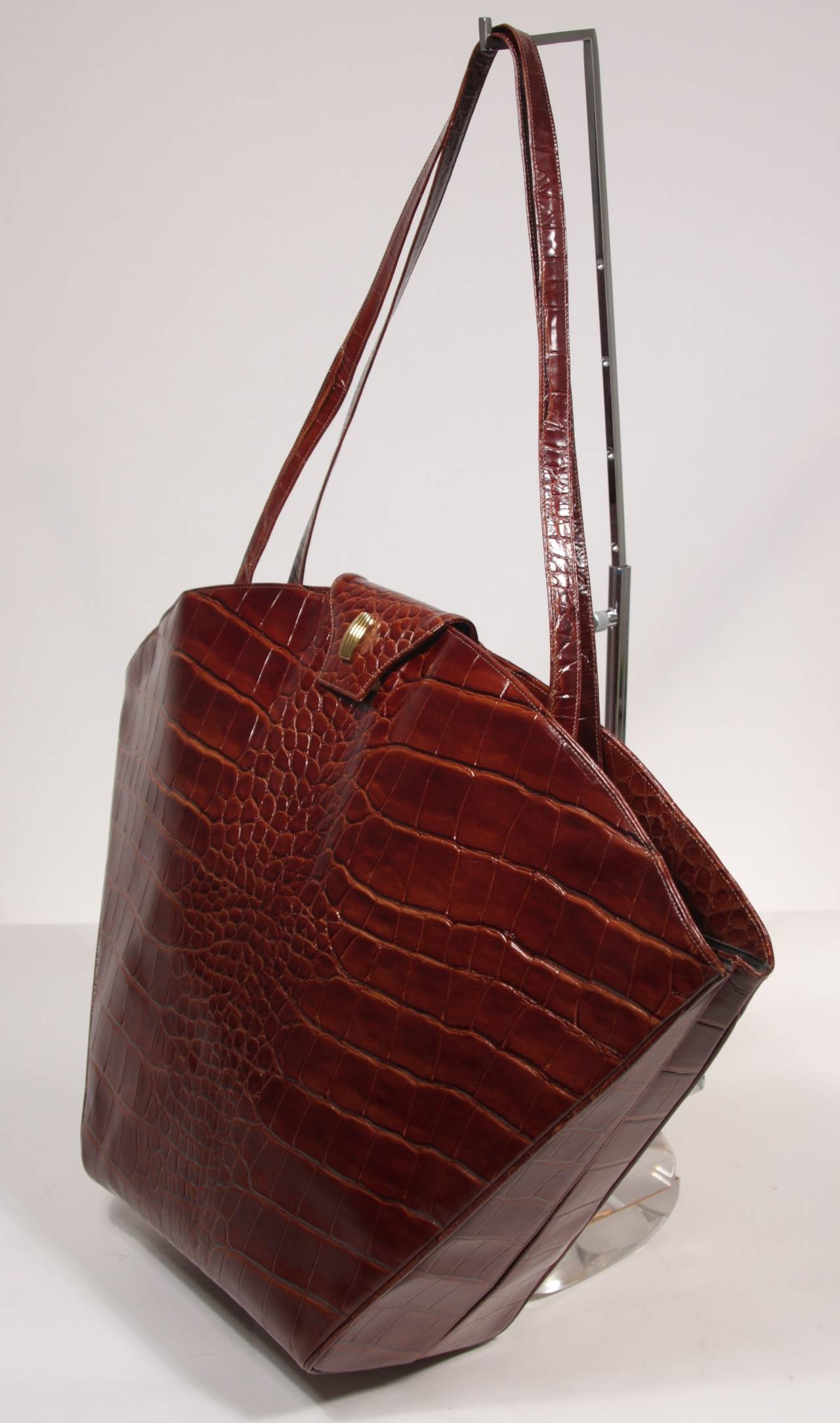 This is a Carey Adina design. This fabulous extra large handbag is stunning. It's extra large size is complemented by a fan shape and design. The bag is composed of a brown/cognac leather and embossed with a crocodile print. There are two interior