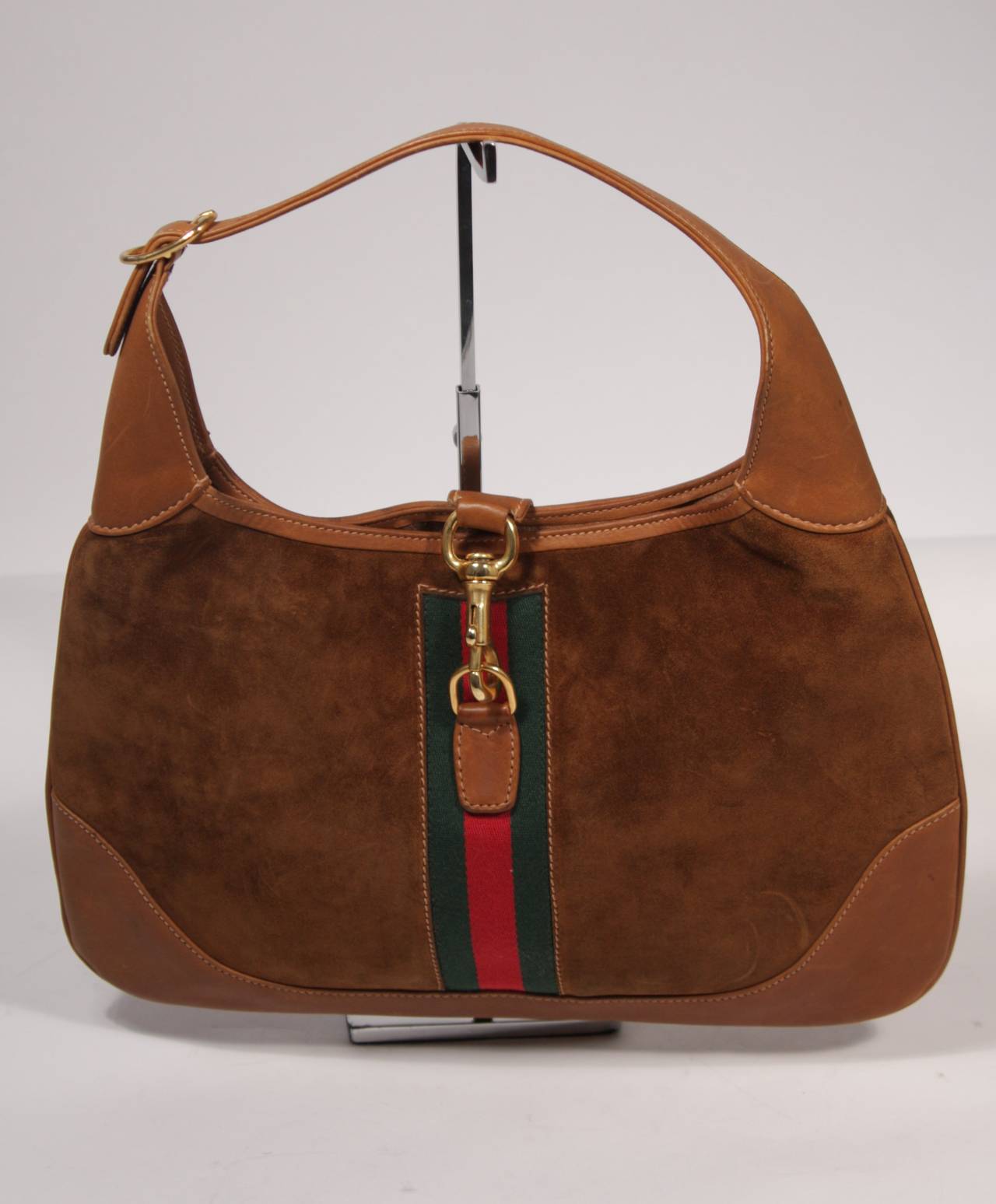 This is a Gucci vintage handbag. The hobo style purse is composed of a rich brown leather and suede. It is accented with the classic Gucci green and red strip with gold hardware. The purse is practically unused, possibly never worn. 

Measures