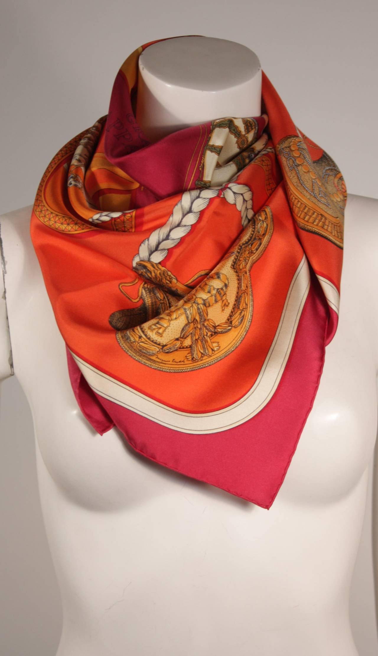 This is a lovely Hermes Grand Apparat scarf. The scarf is in excellent condition and comes with it's original boxes (Christmas gift box and Hermes' original box). The silk scarf features hand rolled edges and a striking print, with contrasting