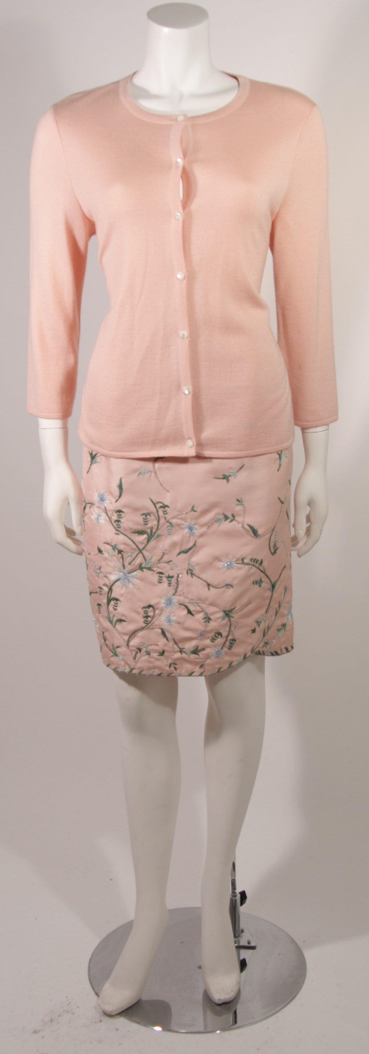 This is an Oscar De La Renta design. This set features a beautiful supple pink cardigan and embroidered skirt. The skirt is composed of a silk/wool blend and is embroidered with a floral motif and accented with a flash of bead work. The skirt