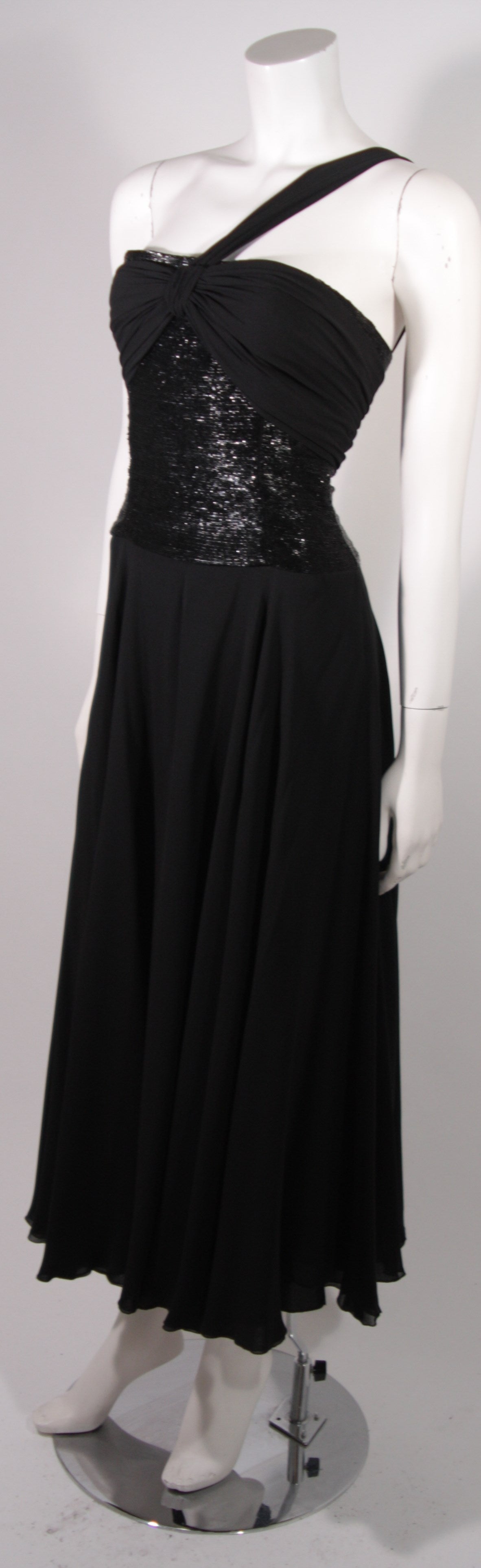 This is a Chloe design. The gown is composed of a black silk chiffon skirt featuring a  gorgeous beaded bodice. There is an asymmetrical chiffon drape across the shoulder and chiffon at the bust. Center back zipper closure. 

Measures
