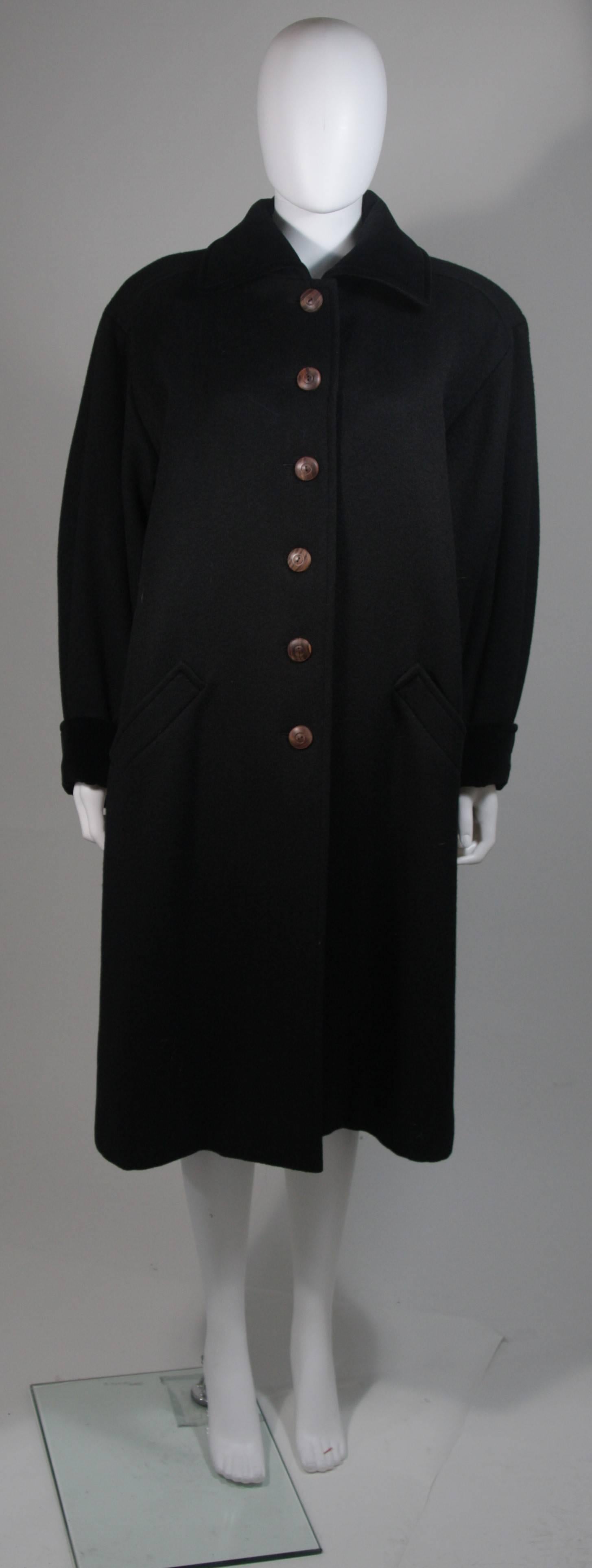This Yves Saint Laurent design is available for viewing at our Beverly Hills Boutique. We offer a large selection of evening gowns and luxury garments. 

 This coat is composed of black wool with velvet trim. The coat features center front wood