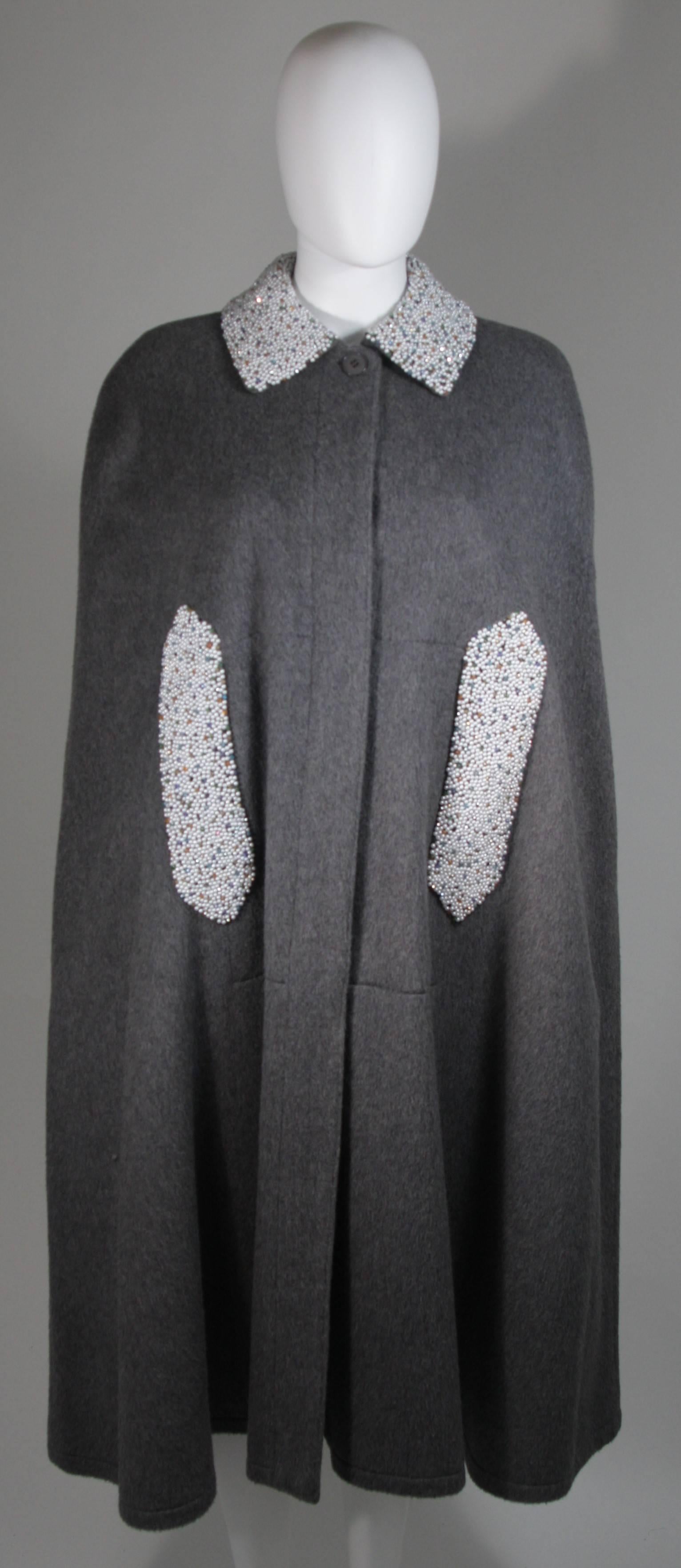  This cape is composed of a grey wool. The cape is a vintage design with a modern twist, the pearl and rhinestone beading at the pockets are a modern addition by 'Vutique'. The cloak has front button closures. In excellent vintage condition. 

 