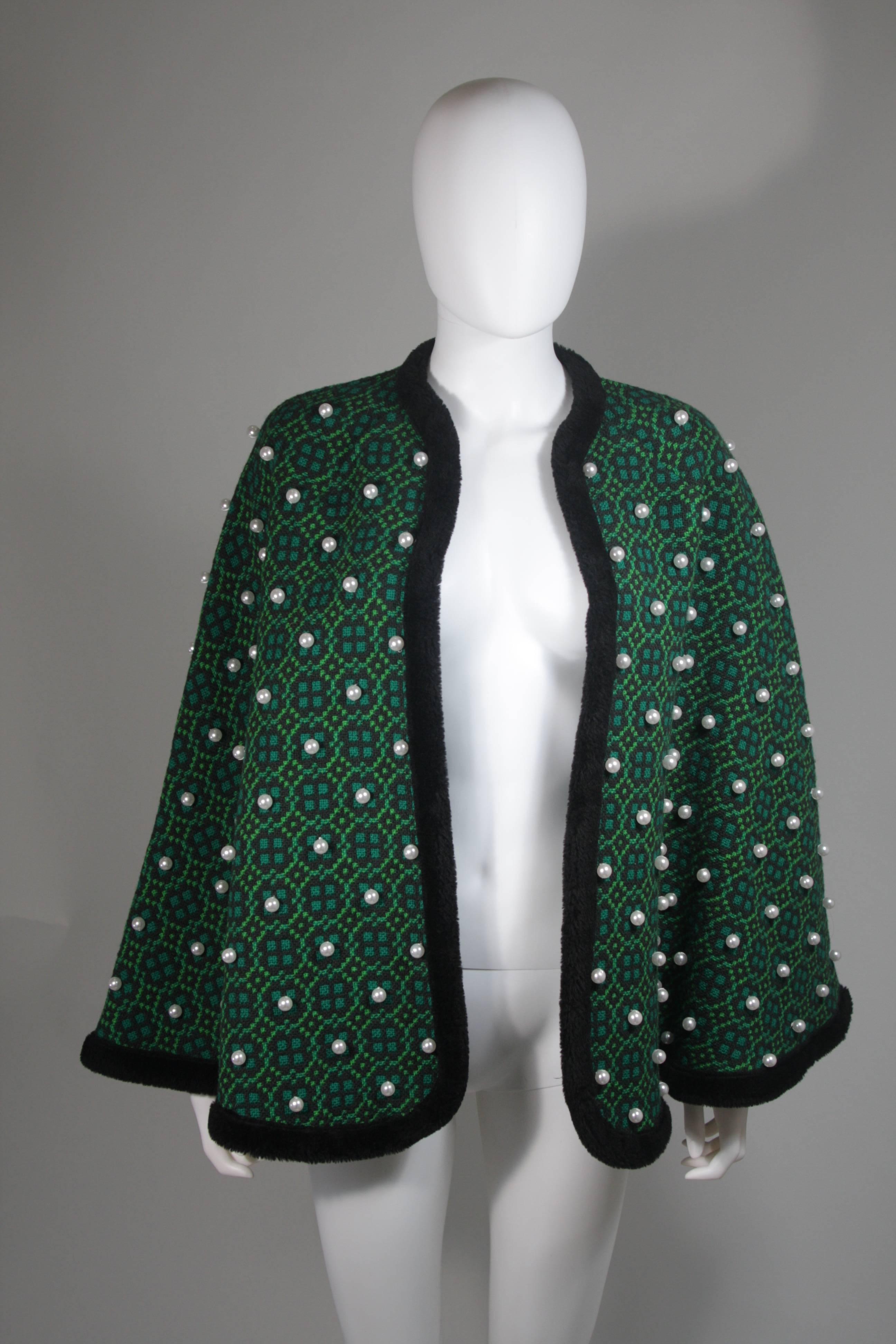  This cape is composed of a green wool with black faux fur trim. The cape is a vintage design with a modern twist, the pearl adornments are a modern addition by 'Vutique'. The cape is an open style. In excellent vintage condition. 

  **Please