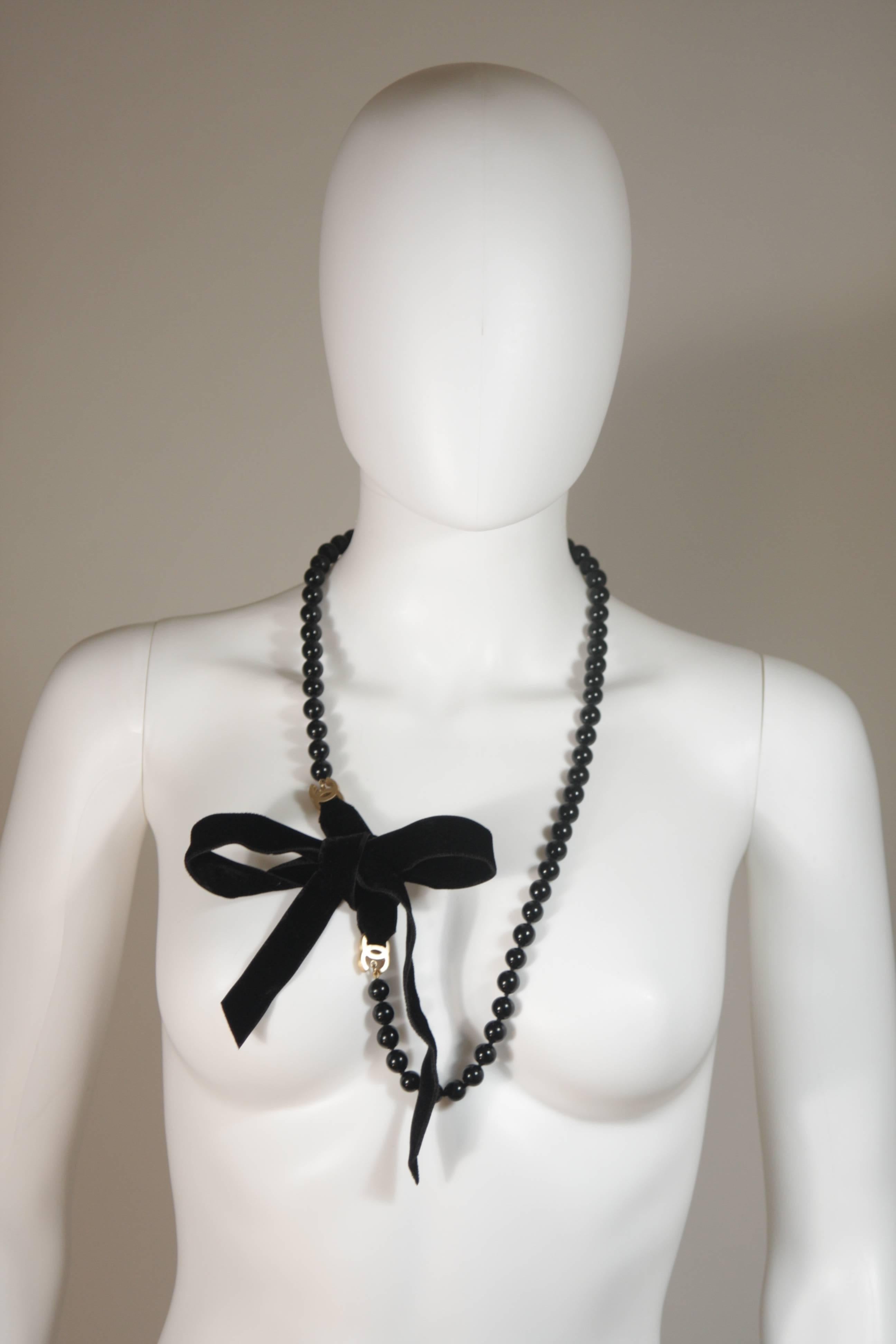 This Chanel design is available for viewing at our Beverly Hills Boutique. We offer a large selection of evening gowns and luxury garments. 

 This Chanel accessory is composed of black beads and features velvet ties with gold hue hardware. In