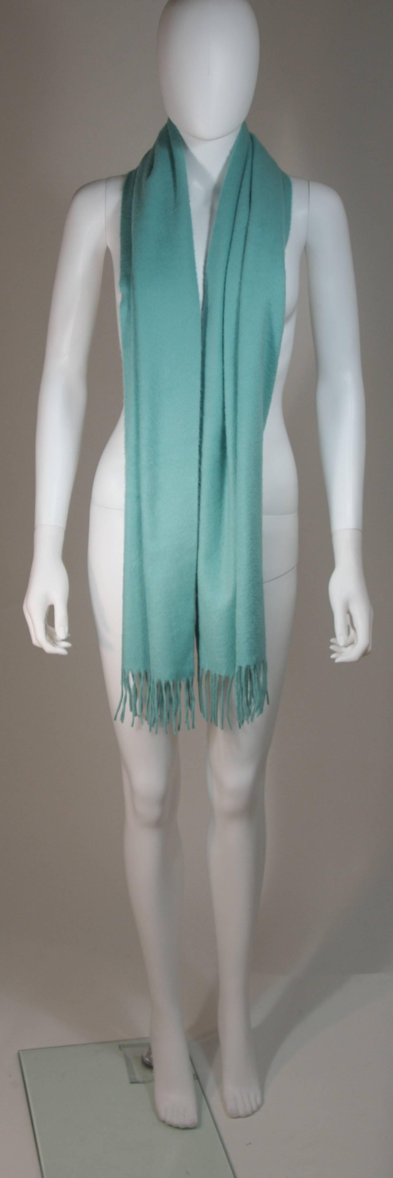 This Yves Saint Laurent design is available for viewing at our Beverly Hills Boutique. We offer a large selection of evening gowns and luxury garments. 

 This scarf is composed of an ultra soft cashmere in an aqua hue. Features fringe ends. In