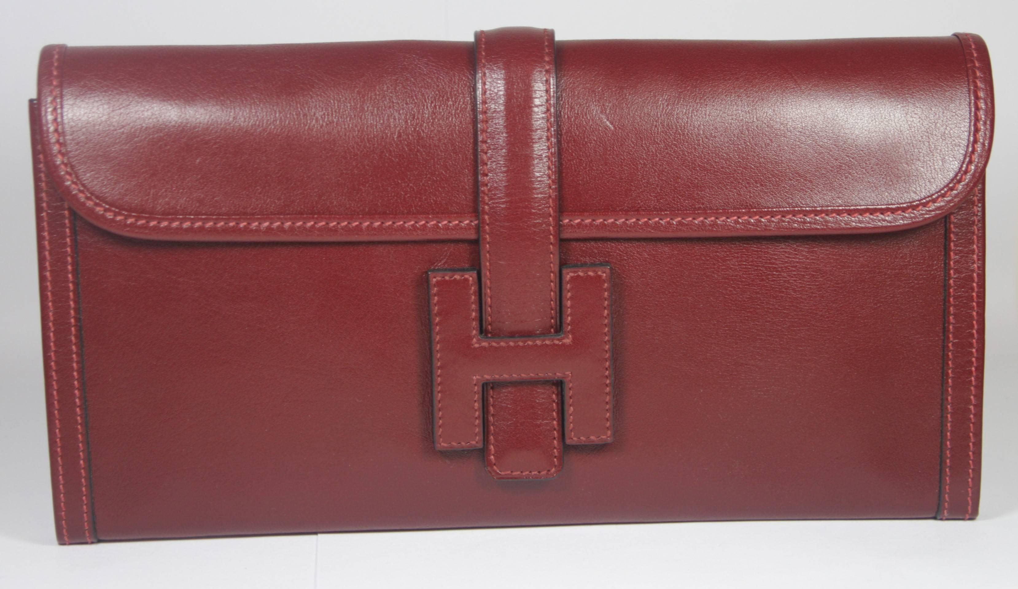 This Hermes design is available for viewing at our Beverly Hills Boutique. We offer a large selection of evening gowns and luxury garments. 

 This clutch is composed of a beautiful burgundy leather with top stitch detailing. In excellent vintage