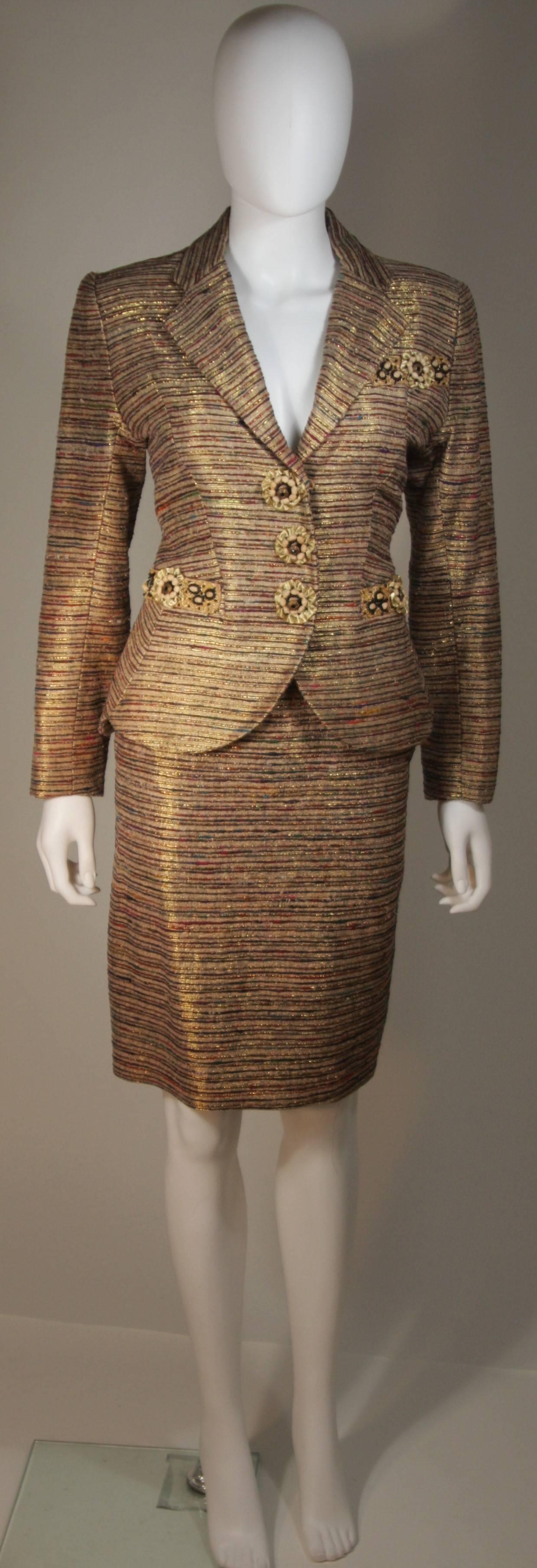 This Zandra Rhodes  skirt suit is composed of a metallic raw silk in hues of bronze to burgundy. There are applique details on the jacket as well as center front snap closures. The skirt is a classic pencil style with zipper closures. In excellent