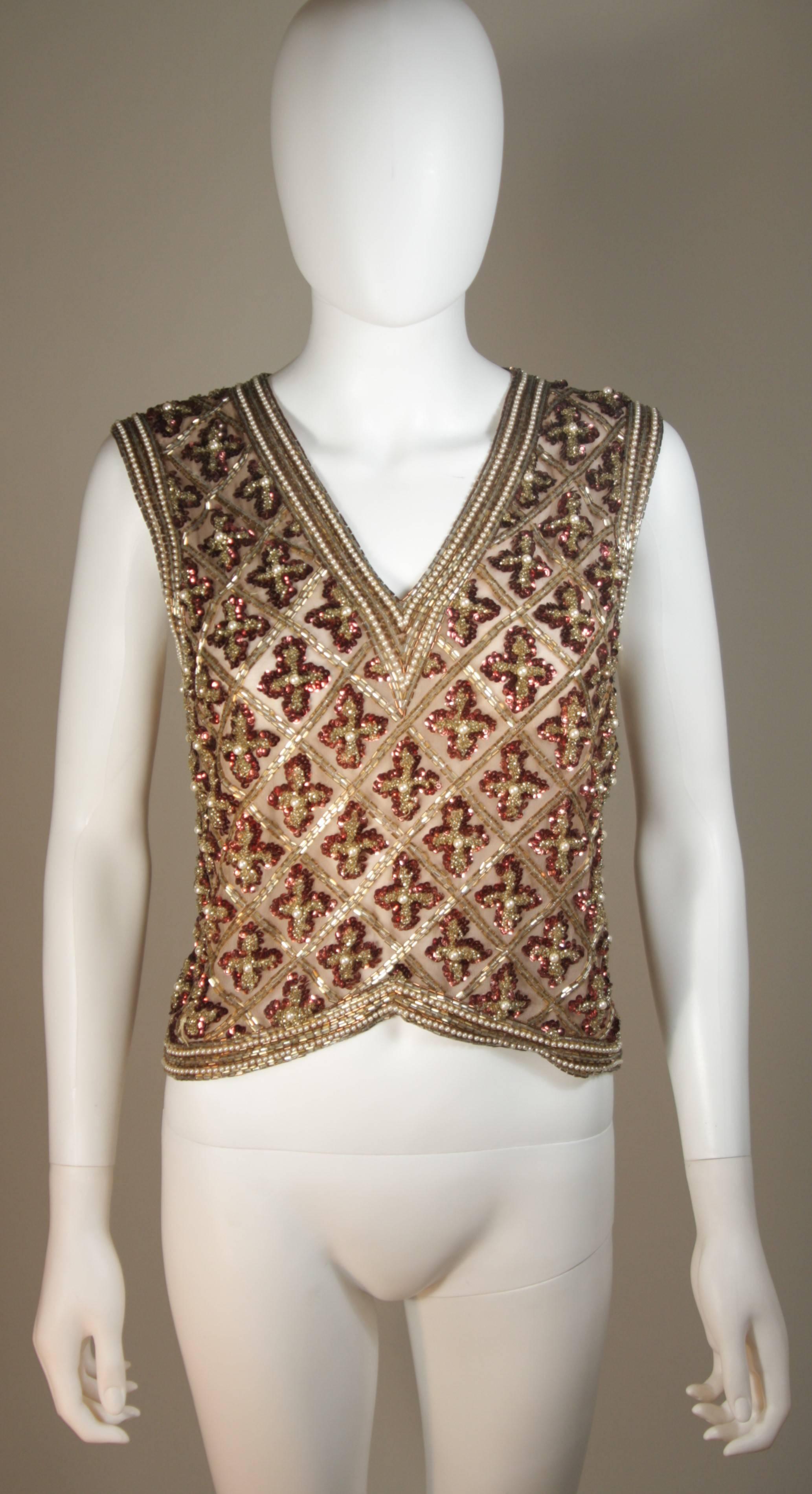 This Galanos  blouse is composed of a beaded and sequin appliqued silk, in gold and burgundy hues. The top features a 3-dimensional beading technique. There are center back hook and eye closures. In excellent condition.

  **Please cross-reference