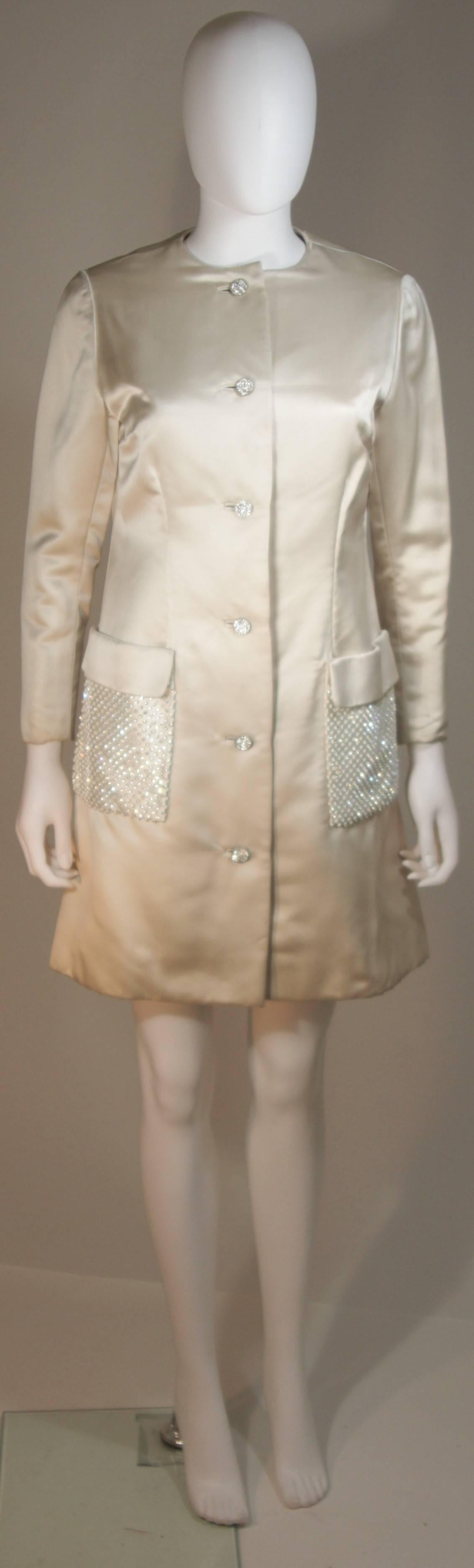 This Shedlock coat style dress is composed of an off-white silk and features rhinestone adorned pockets. There are center front rhinestone closures as well as snaps. In excellent vintage condition. Made in Italy.

**Please cross-reference