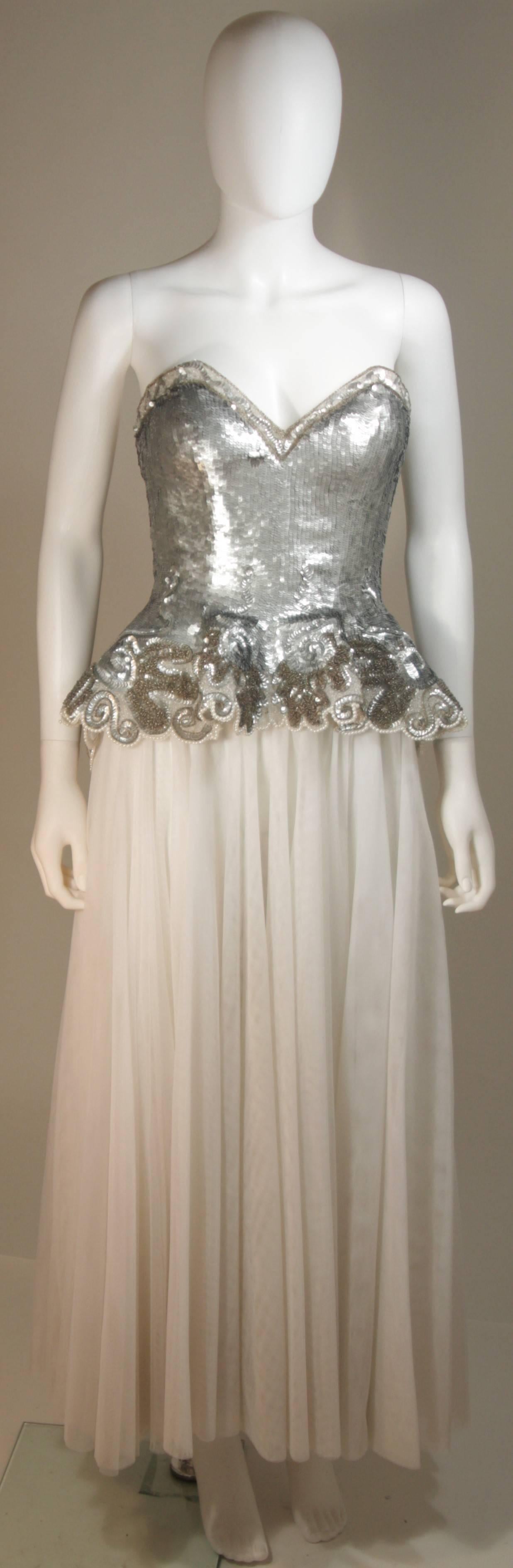 This Fabrice New York Couture  gown is composed of a silver sequined bustier with white mesh skirt. There is a zipper back closure and peplum style. In excellent condition. 

  **Please cross-reference measurements for personal accuracy.