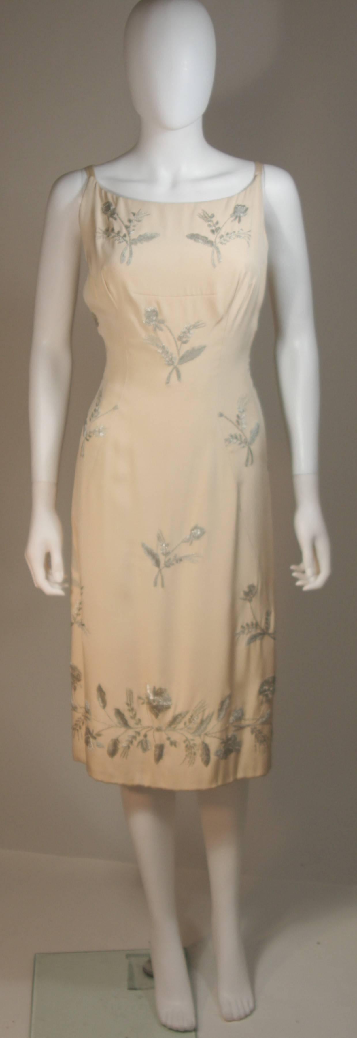 Dieser Martier Raymond  das Kleid ist aus elfenbeinfarbener Seide gefertigt und mit silbernen Metallblumenapplikationen versehen. Es hat einen Reißverschluss und Prinzessinnenabnäher. In ausgezeichnetem Vintage-Zustand. Hergestellt in Italien.

 