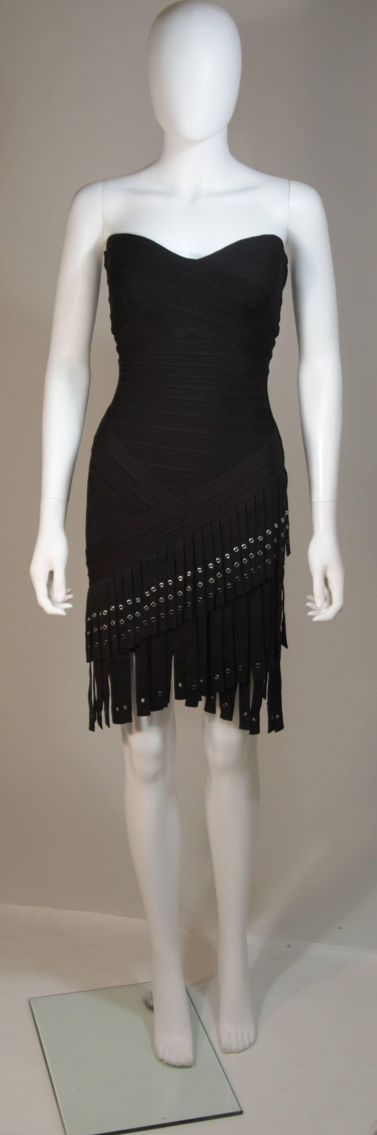 This Herve Leger design is available for viewing at our Beverly Hills Boutique. We offer a large selection of evening gowns and luxury garments. 

 This dress is composed of a black elastic with fringe and grommet details. There is a center back