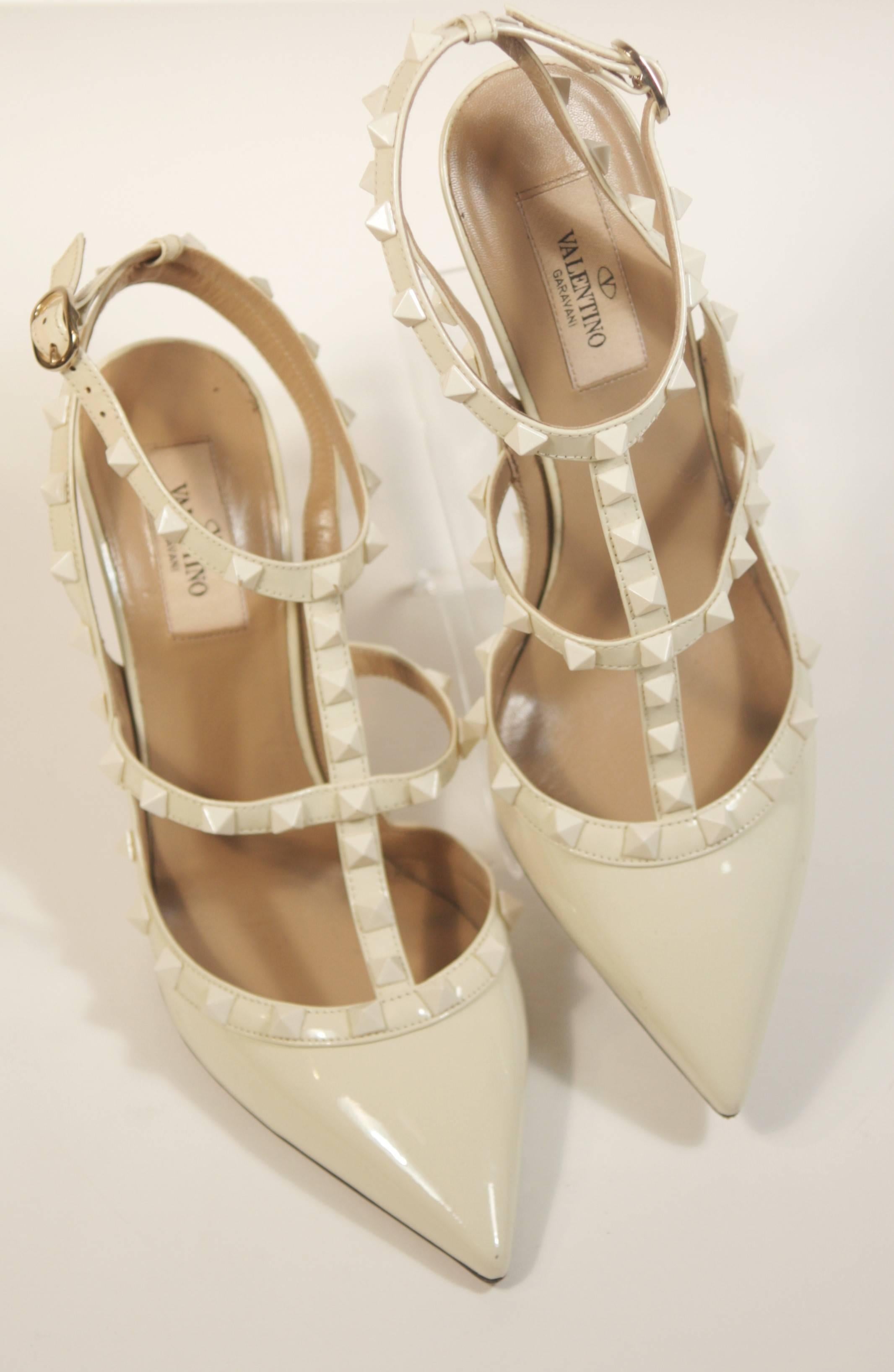 This Valentino design is available for viewing at our Beverly Hills Boutique. We offer a large selection of evening gowns and luxury garments. 

 These Valentino pumps are composed of an ivory hue patent leather, called 'Bone'. Features studded
