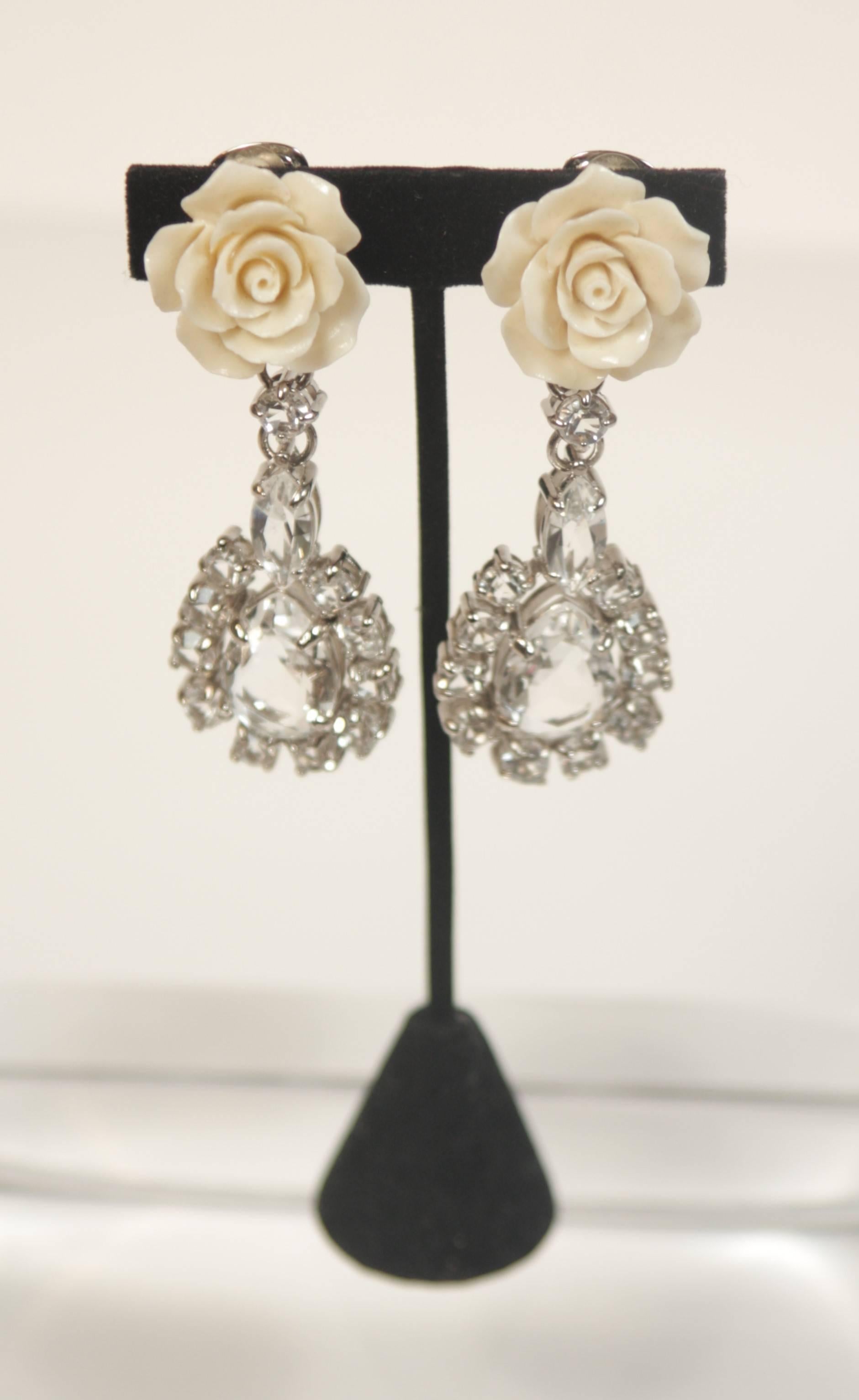 This Prada design is available for viewing at our Beverly Hills Boutique. We offer a large selection of evening gowns and luxury garments. 

 These earrings are composed of a silver tone metal with large set rhinestones and a cream hue rose