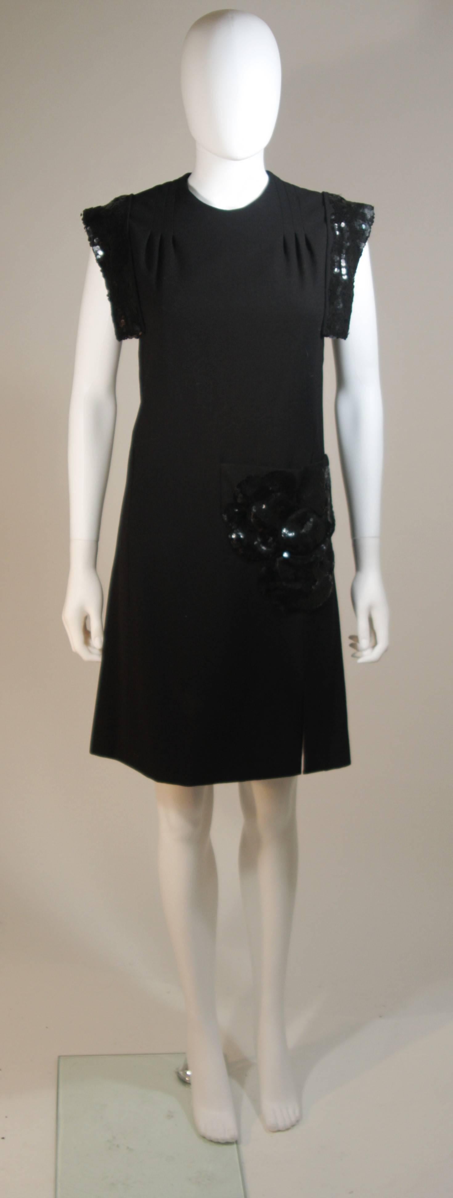 This Carven Couture dress is composed of a black fabric with sequin applique at the shoulders and a flower on a the front pocket. Features a darted shoulder design and zipper closure. In excellent condition. Made in France.

  **Please