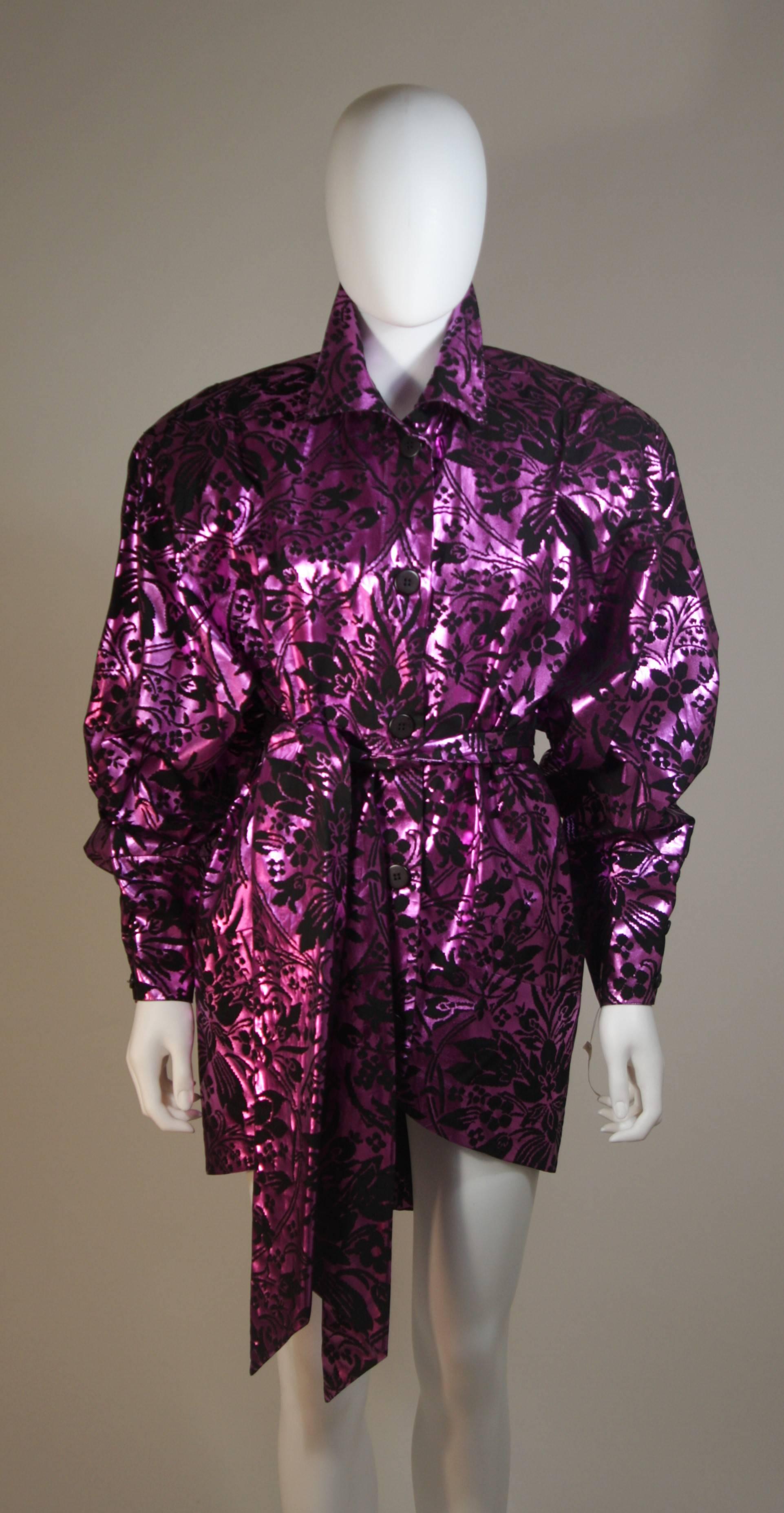 This Byblos for Amen Wardy dress is composed of a black fabric with purple metallic foiling in an abstract floral motif. There are center front button closures, shoulder pads, and a belt. In excellent condition. Made in Italy.

  **Please