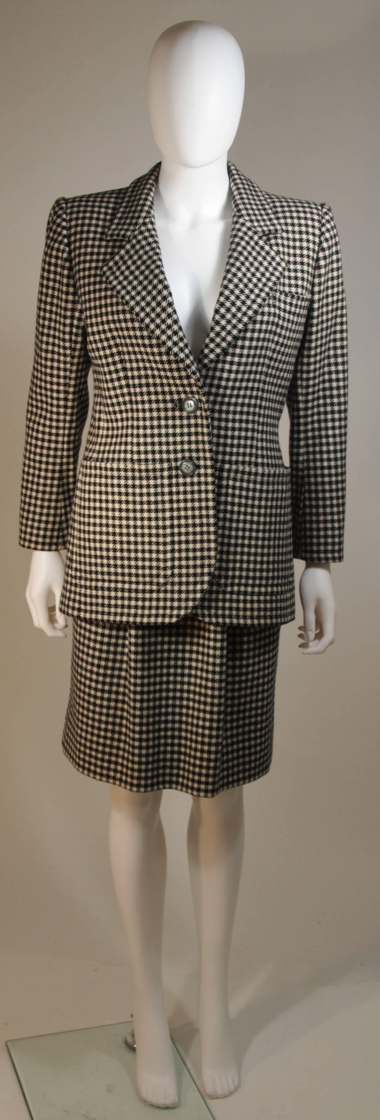 This Yves Saint Laurent skirt suit is composed of a black and white wool featuring a houndstooth print. The jacket has center front button closures. The skirt has a zipper closure. In excellent condition. 

**Please cross-reference measurements