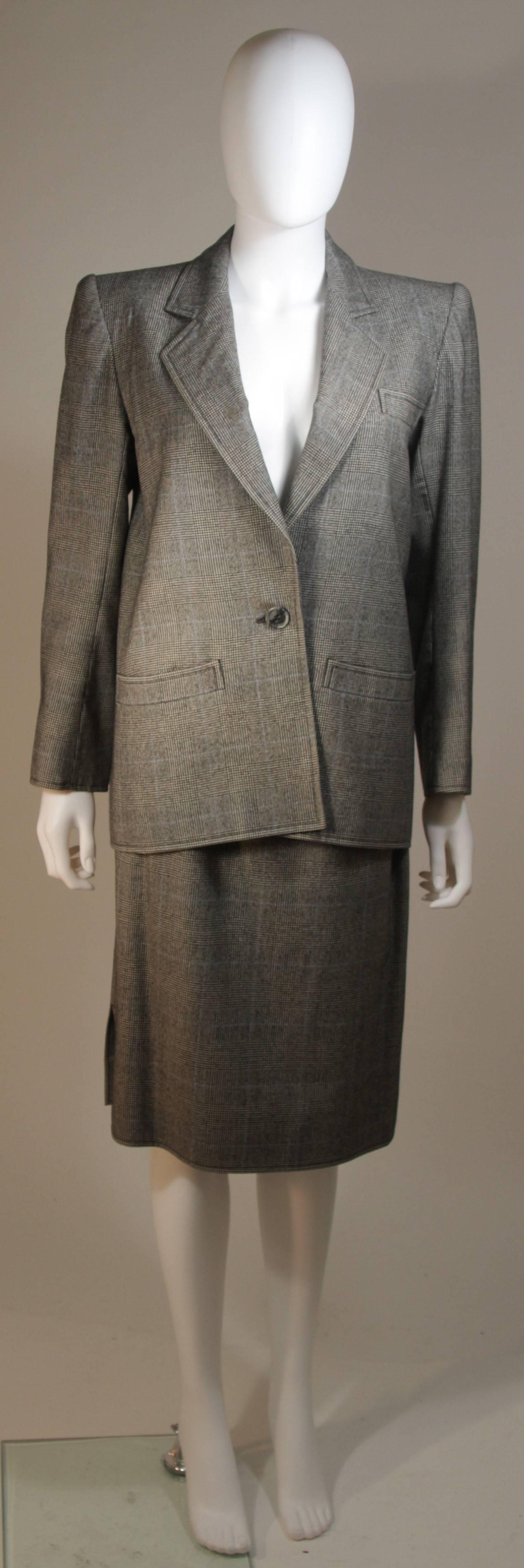 This Yves Saint Laurent skirt suit is composed of a grey plaid wool with blue accents. The jacket has center front button closures. The skirt has a zipper closure. 

There is a small moth hole, center back. Sold 'As Is'

**Please cross-reference