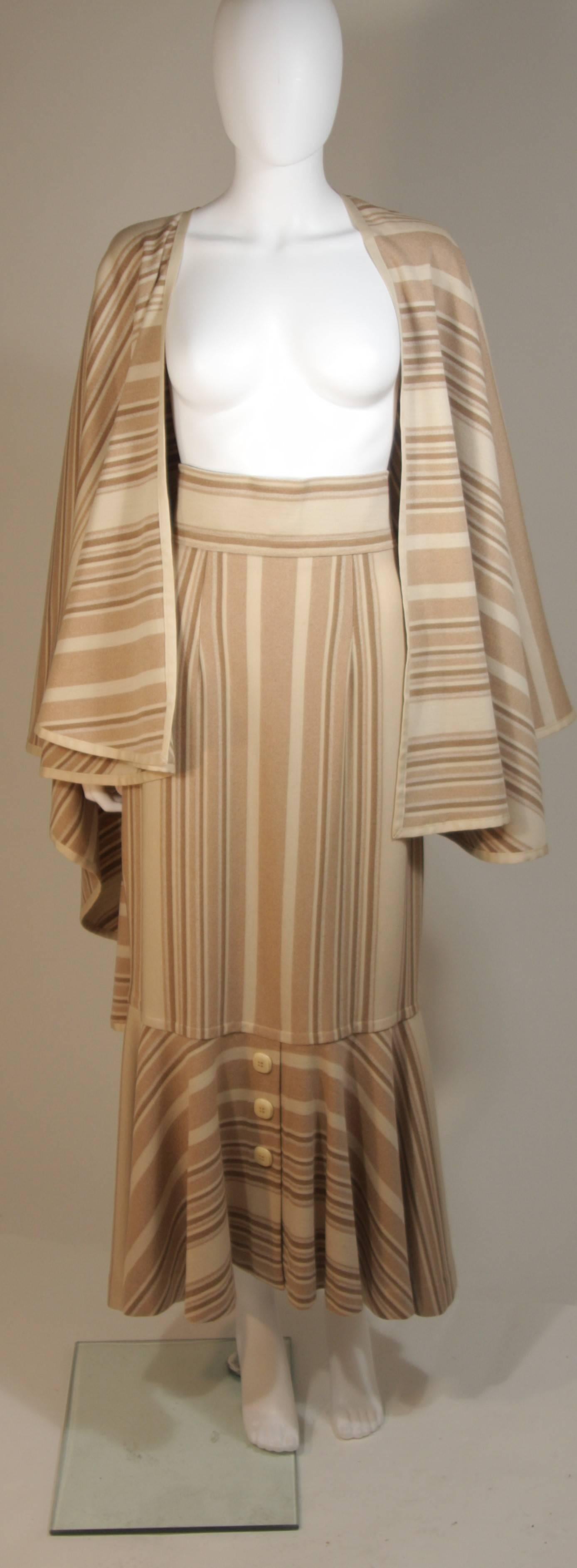 This custom 1960's ensemble is composed of a wonderful wool in beige, nude, and cream hues. The cape features an open style and the skirt has a center back zipper closure with center front button accents at the flared hem. In excellent vintage