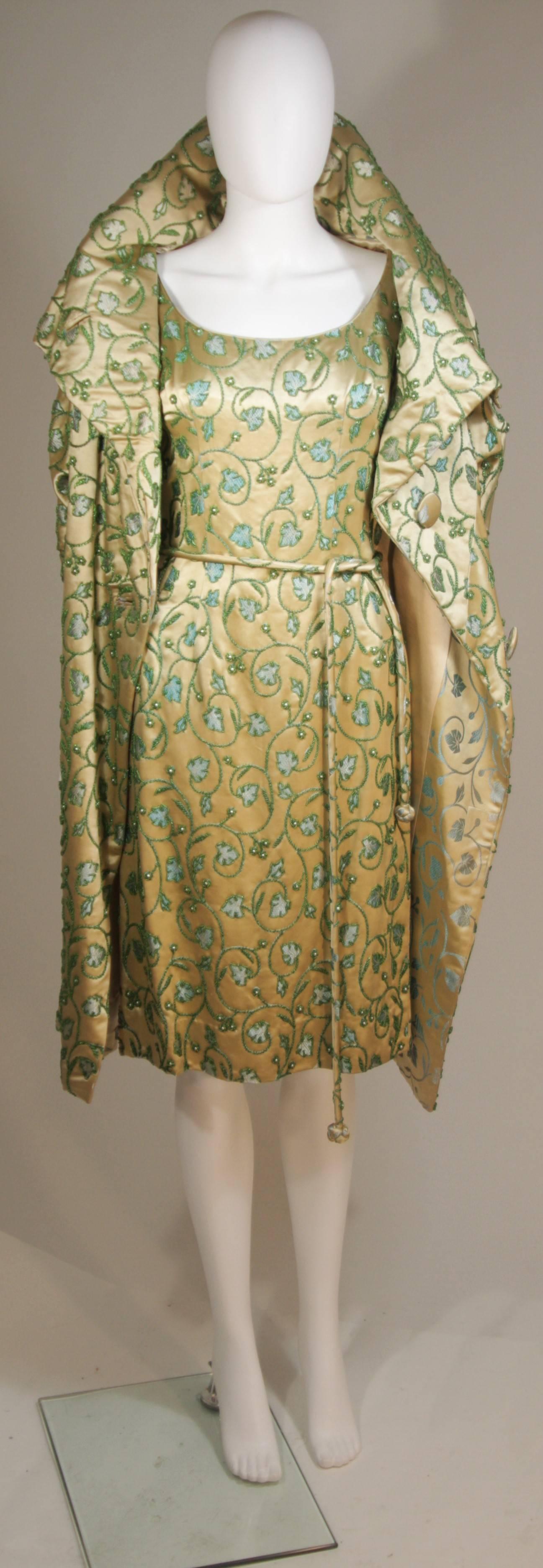 This Haute Couture International ensemble is composed of a champagne tone embellished silk with a floral/Ivy motif. The coat features center button closures and the gown has a center back zipper closure with belt. In excellent vintage condition.