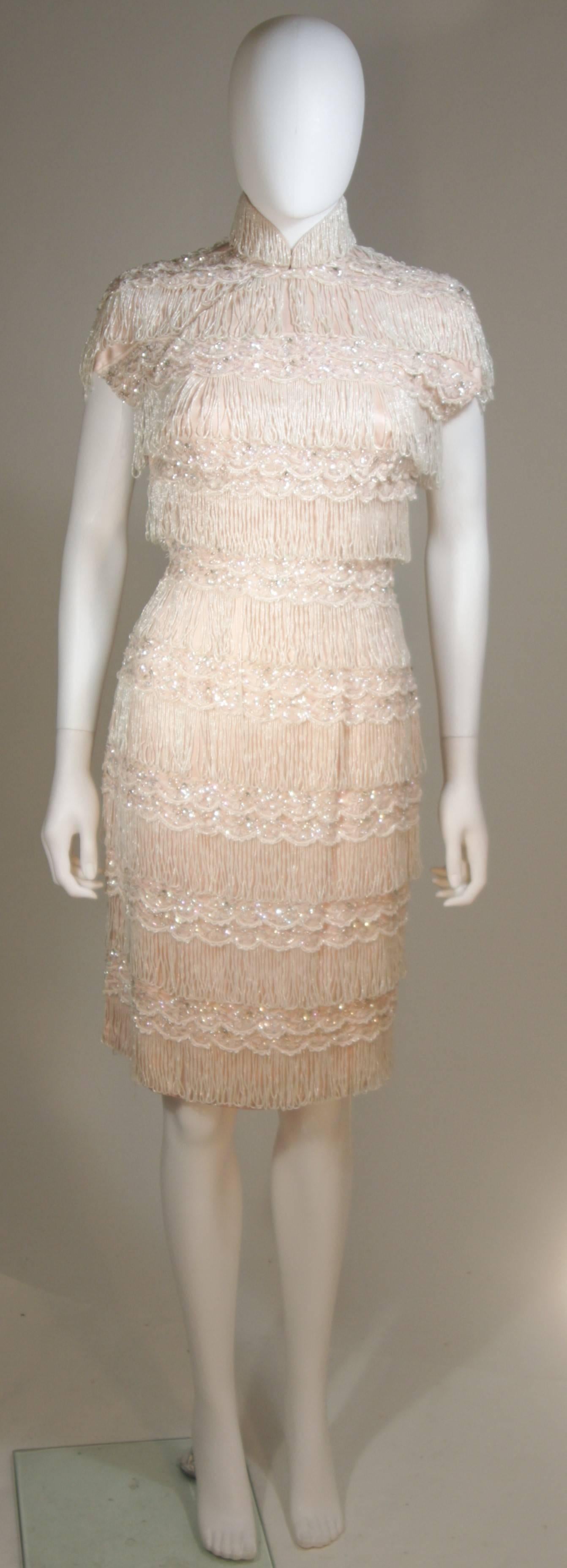  This Haute Couture International  cocktail dress is composed of a pink silk with heavy bead embellishment. There is a mandarin style collar and side zipper with snap front closures. In excellent vintage condition. 

  **Please cross-reference