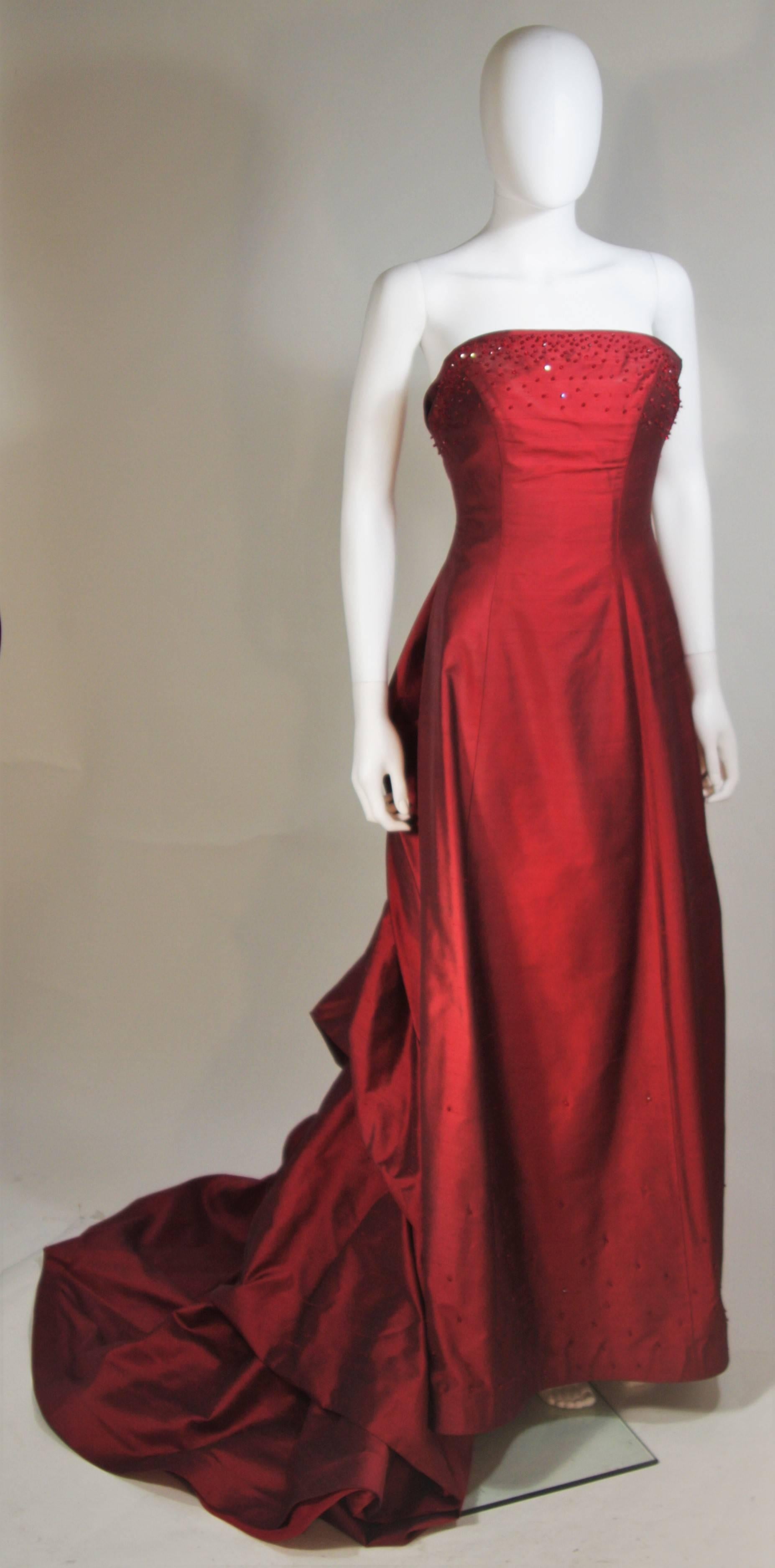  This Daniel James Cantu COUTURE gown is composed of a burgundy raw silk chiffon with bead applique and flower at the center back. There is a center back zipper closure and train. In great condition. 

  **Please cross-reference measurements for