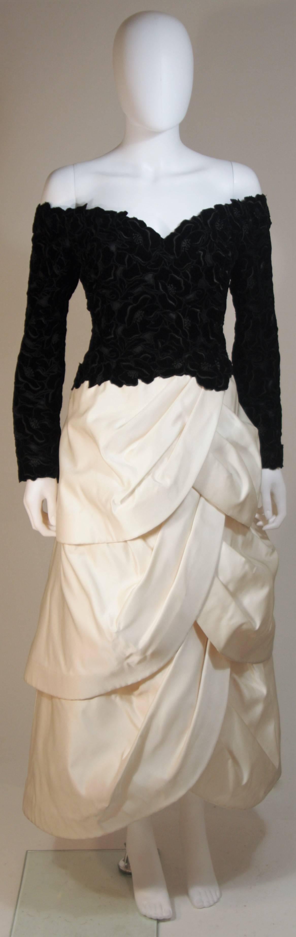  This Arnold Scaasi Couture gown is composed of a black velvet bodice fabricated from floral cut-outs and an off white tiered silk satin skirt. The gown has an off the shoulder style design with sweetheart neckline. There is a center back zipper