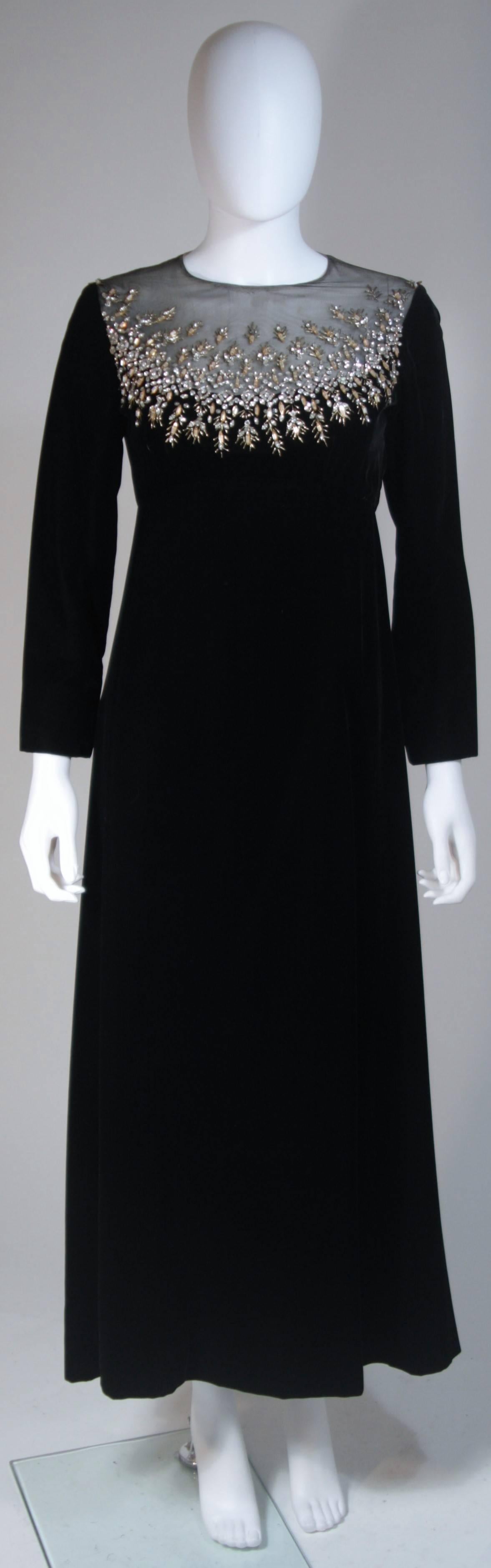  This Malcolm Starr  gown is composed of a black velvet and features a sheer neckline with rhinestone applique. There is a center back zipper. In excellent vintage condition. 

  **Please cross-reference measurements for personal accuracy.
