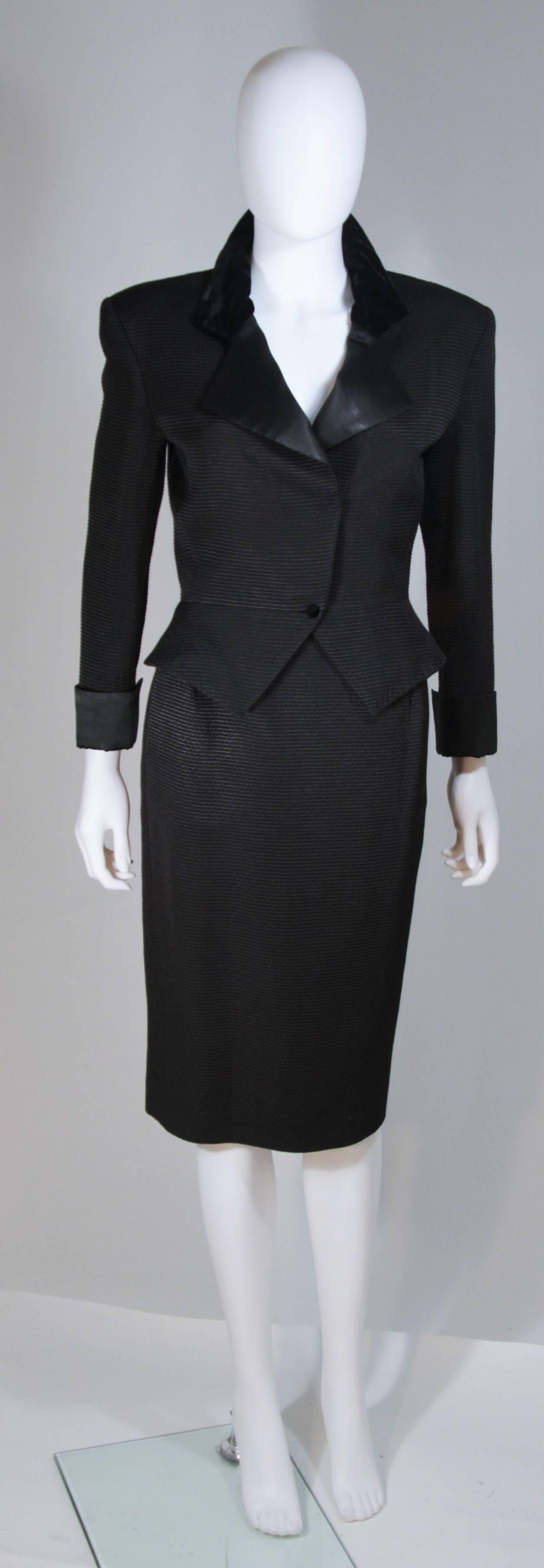  This Carven Couture skirt suit is composed of a black pin-tuck style fabric (cotton/viscose) with satin trim at the sleeves and velvet collar. The jacket features a peplum style with center front button closures. The skirt is a classic pencil style