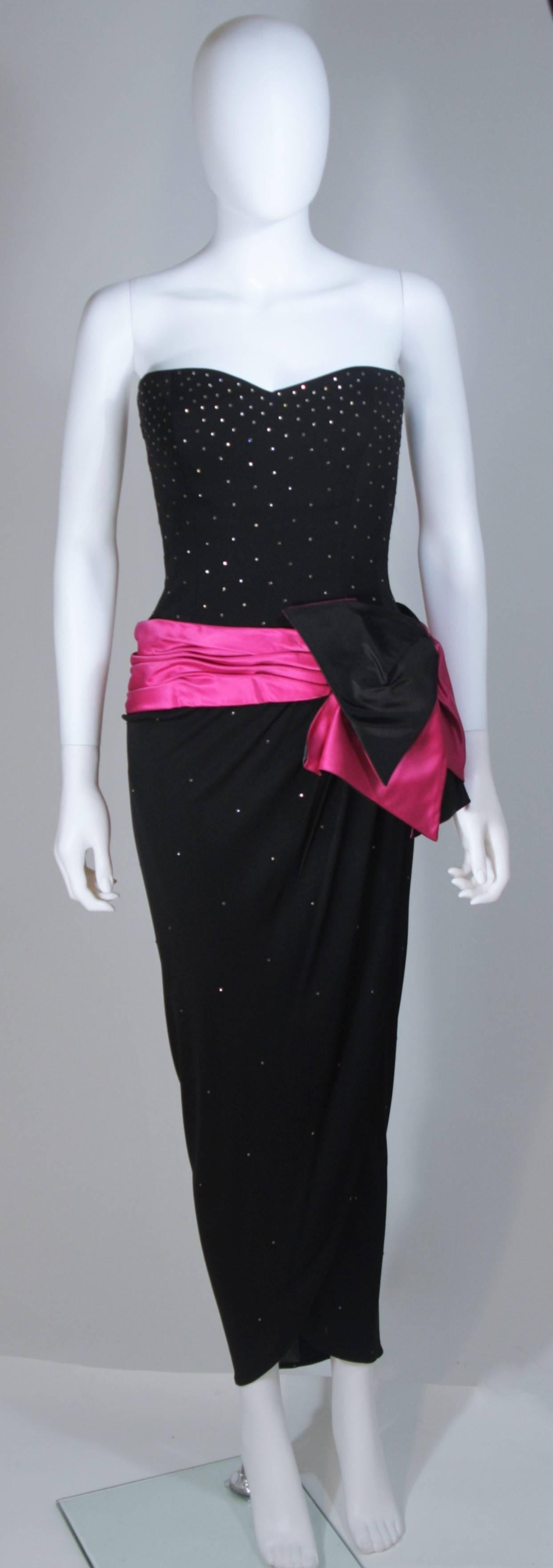  This Tracey Mills gown is composed of a black jersey and features a magenta/purple hue contrast at the waist which is accented by an asymmetrical drape skirt. The bodice is adorned with rhinestones. There is a center back zipper closure. In