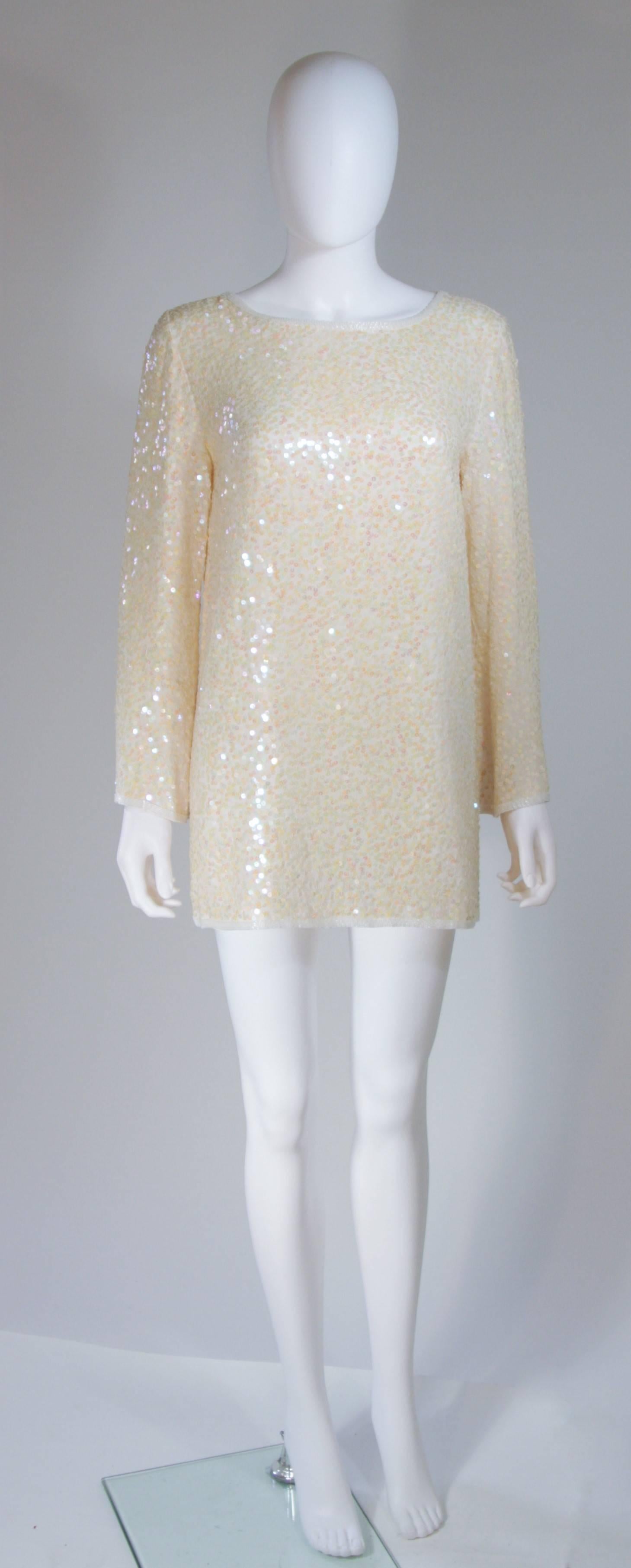 This Oleg Cassini  tunic is composed of an off-white iridescent sequined silk. Features side slits with white beading embellishment, there is a center back zipper closure. In great vintage condition. 

  **Please cross-reference measurements for