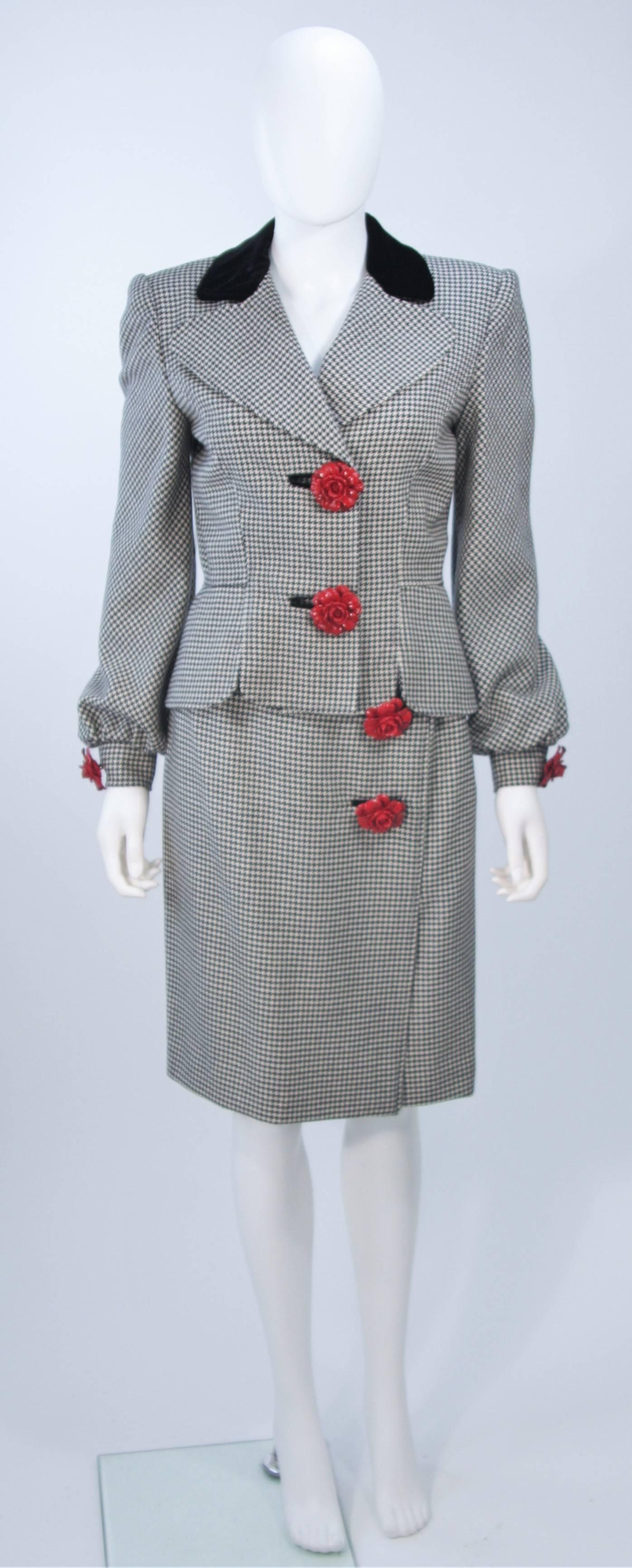  This Valentino skirt suit is composed of a black and white houndstooth print wool and cashmere blend with velvet trim. There are large rose button accents. The jacket features a peplum style and center front closures. The skirt has a pencil style