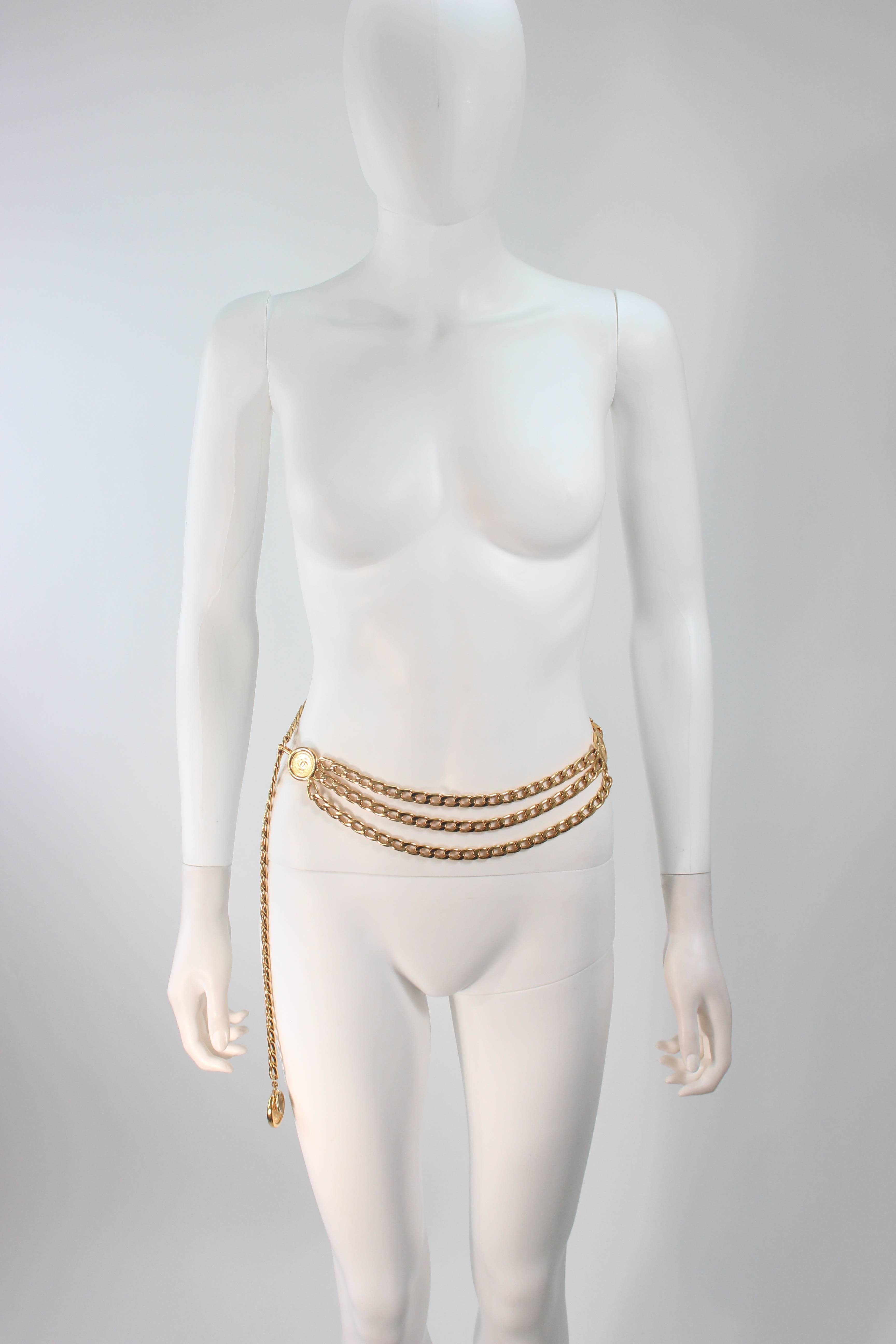 This Chanel design is available for viewing at our Beverly Hills Boutique. We offer a large selection of evening gowns and luxury garments. 

 This belt is constructed of a gold hue metal and features a three strand detail with Chanel logos. In