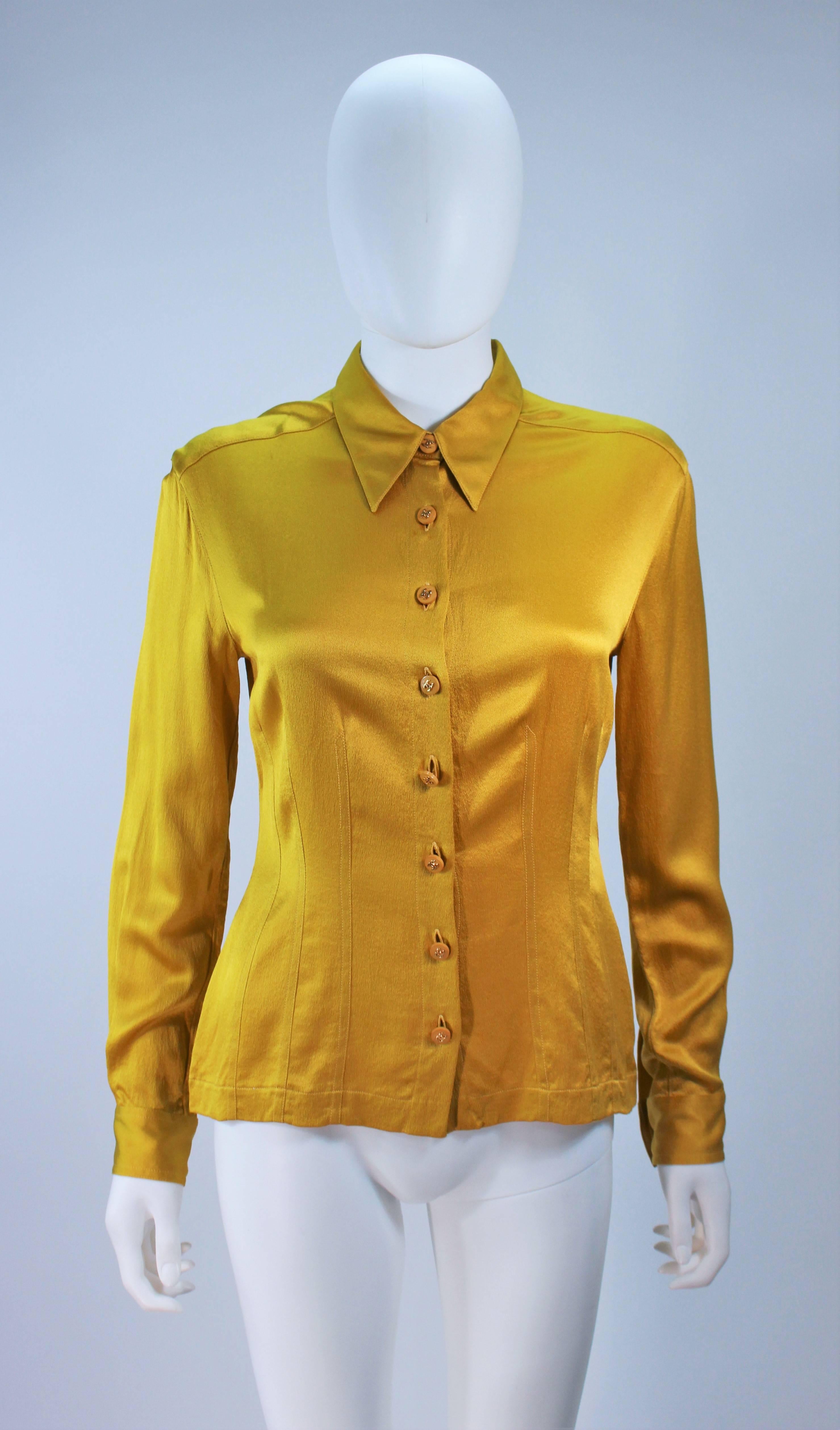  This Chanel blouse is composed of a mustard silk with Chanel 'CC' logo buttons. Features top-stitch waist details. In great condition. 

 **Please cross-reference measurements for personal accuracy. Size in description box is an