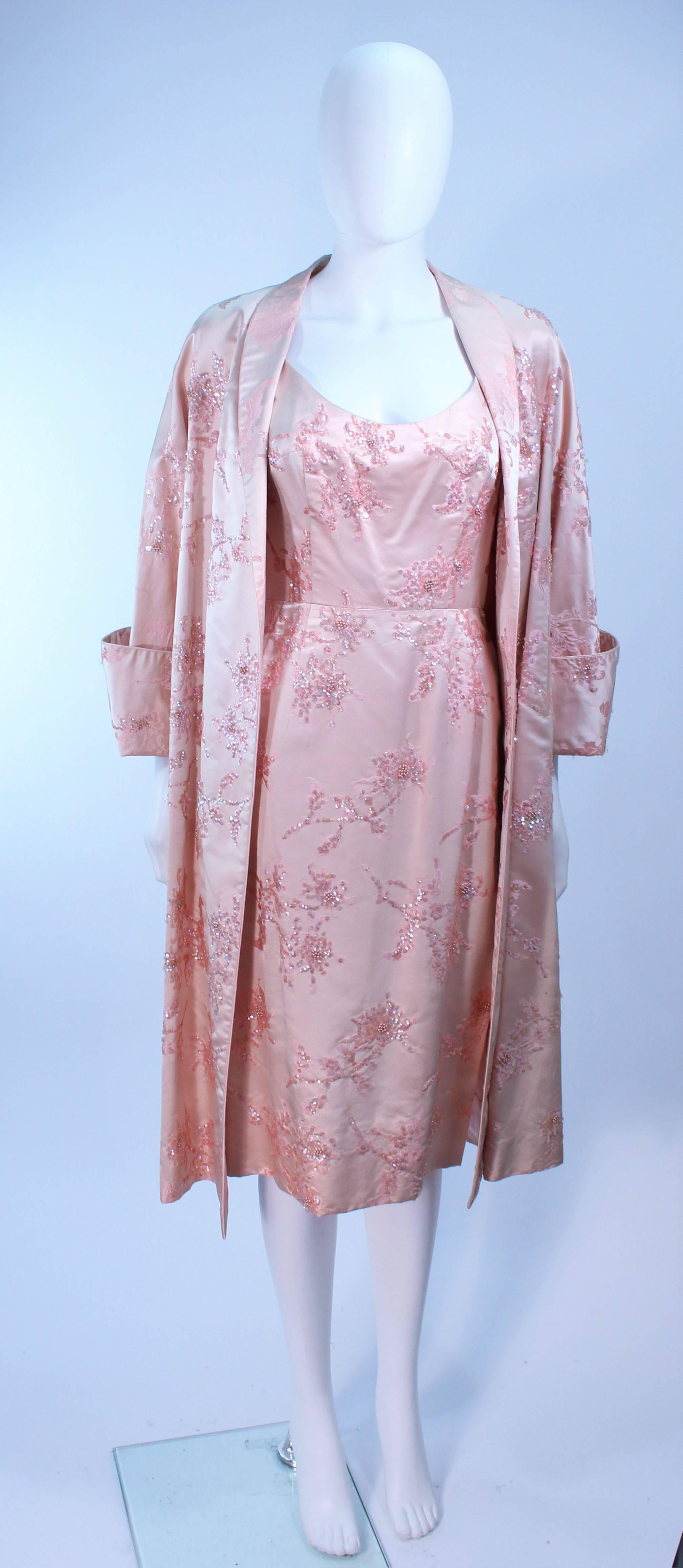 This ensemble is composed of a pink silk with sequin applique. The coat features large cuffs and an open style. The cocktail dress features braided straps and a center back zipper closure. In excellent vintage condition, some discoloration and