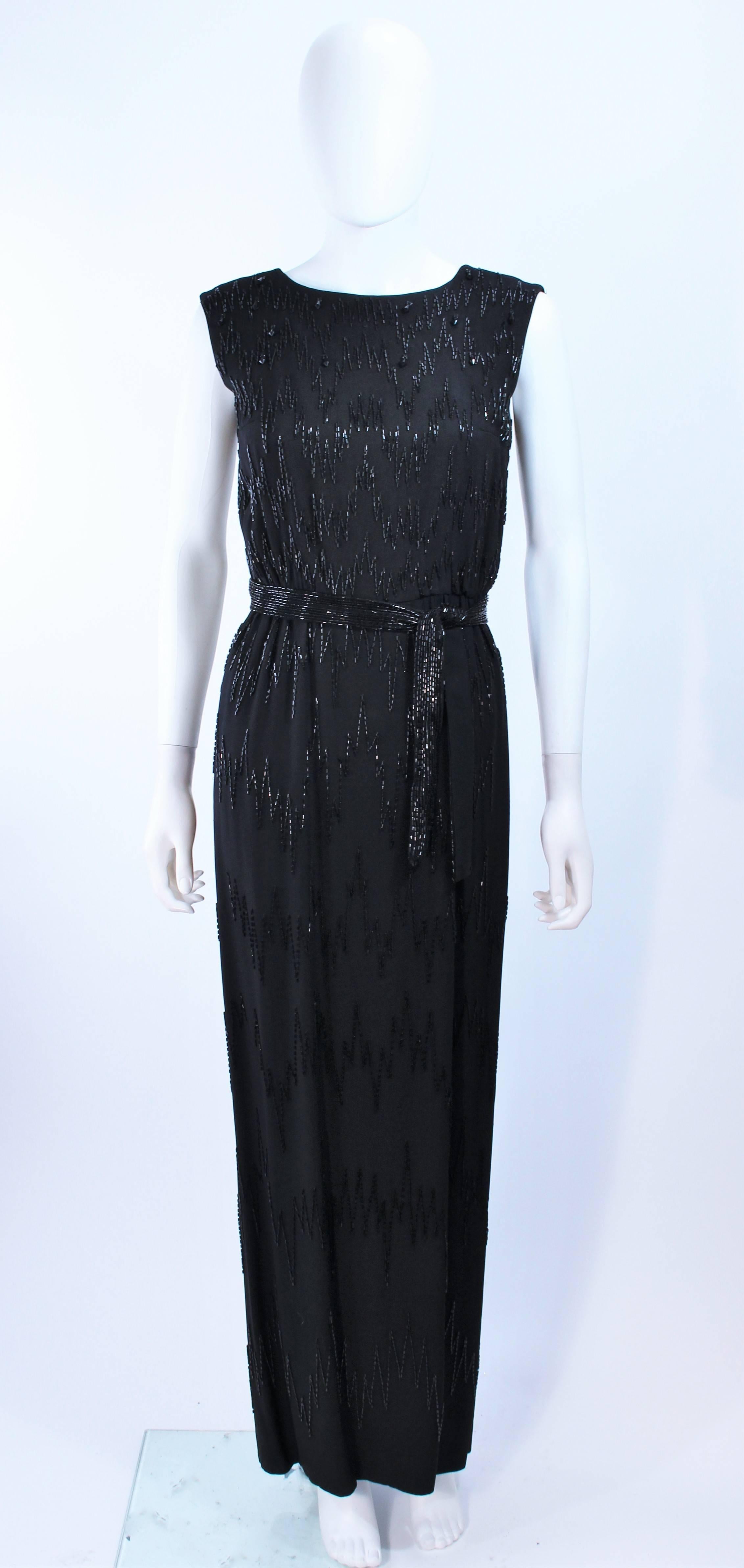This gown is composed of black silk with a zig zag hand beaded applique. Features a beaded belt. There is a center back zipper closure. In excellent vintage condition, some beading missing.

**Please cross-reference measurements for personal
