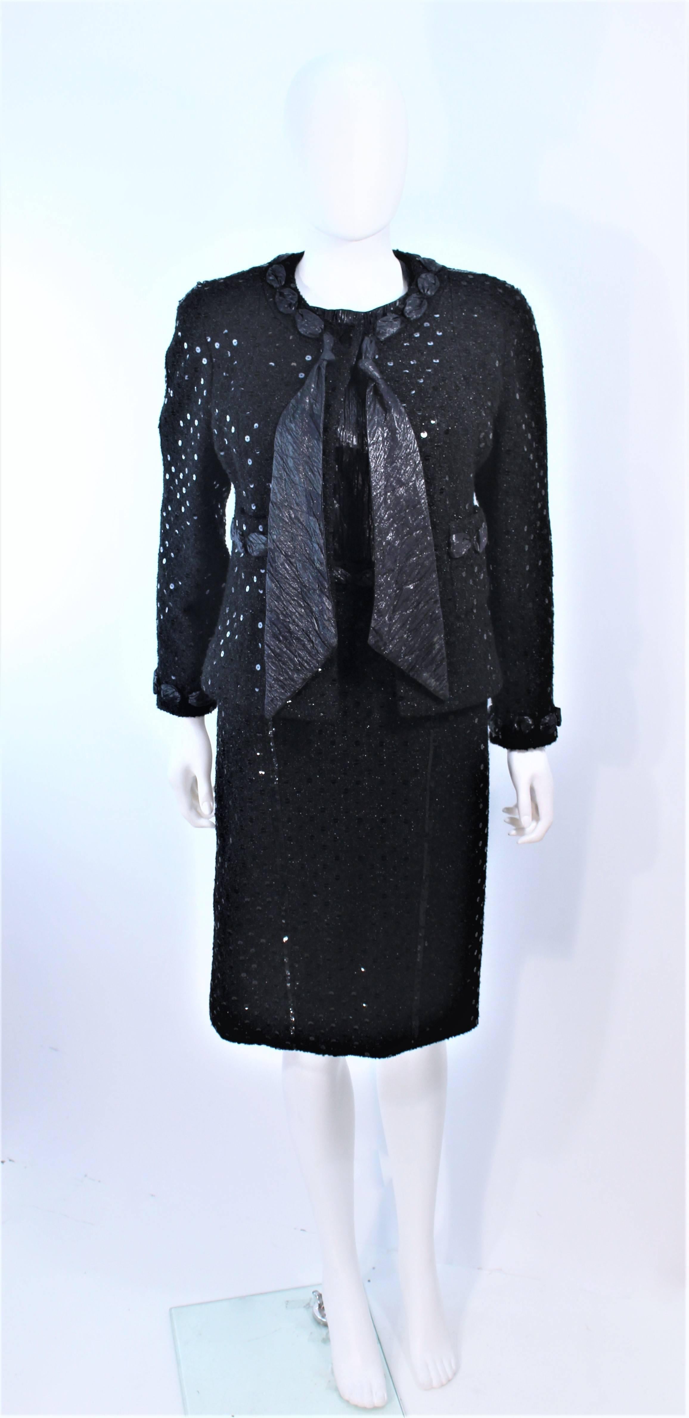 This Chanel skirt suit is composed of black silk lame, and metallic infused wool boucle. The jacket features faceted black center front button closures. the tank style top has a criss-cross back. The skirt has a classic pencil style with zipper