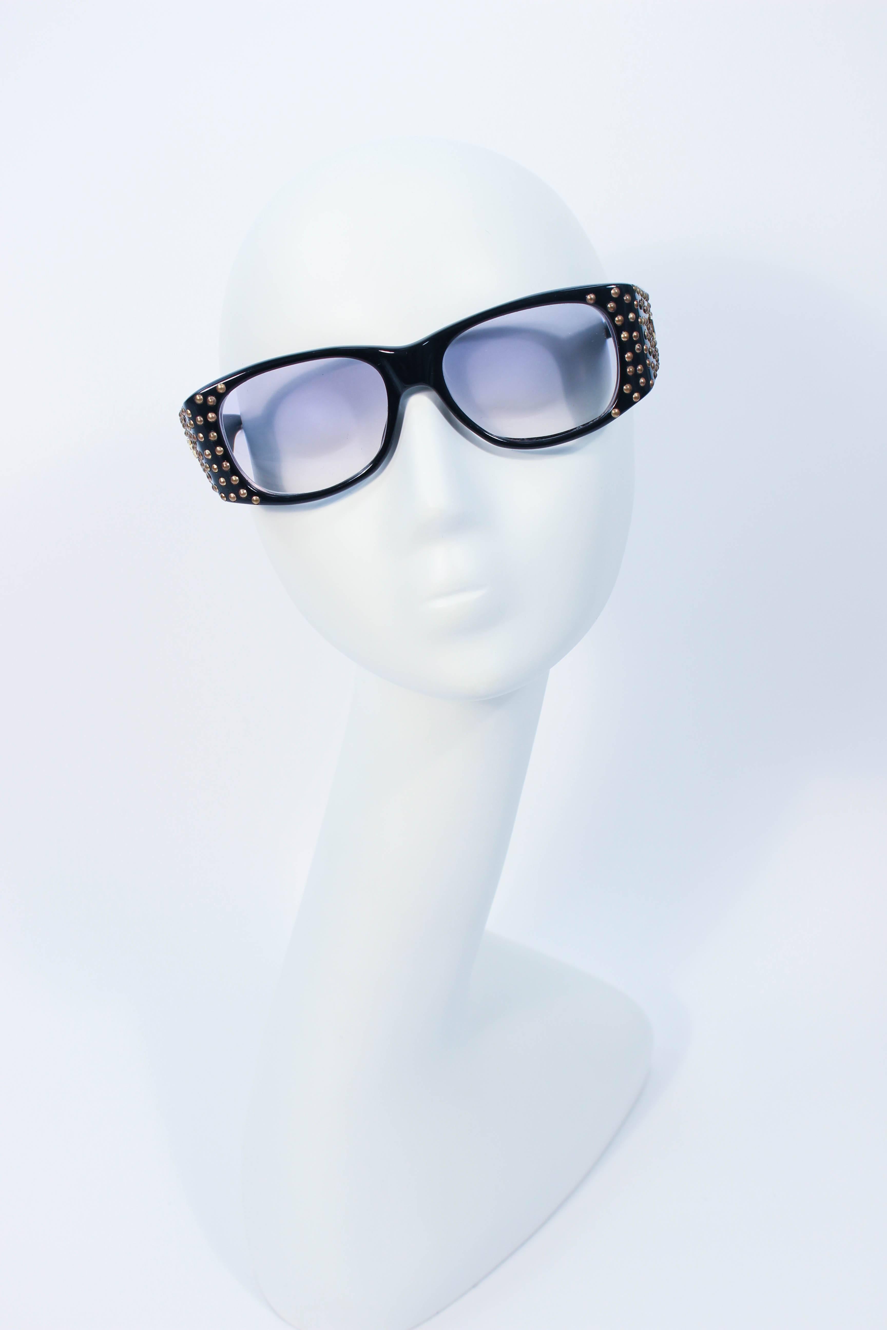 Ces lunettes de soleil Emmanuelle Khanh en plastique noir sont ornées de clous dorés et du logo classique 