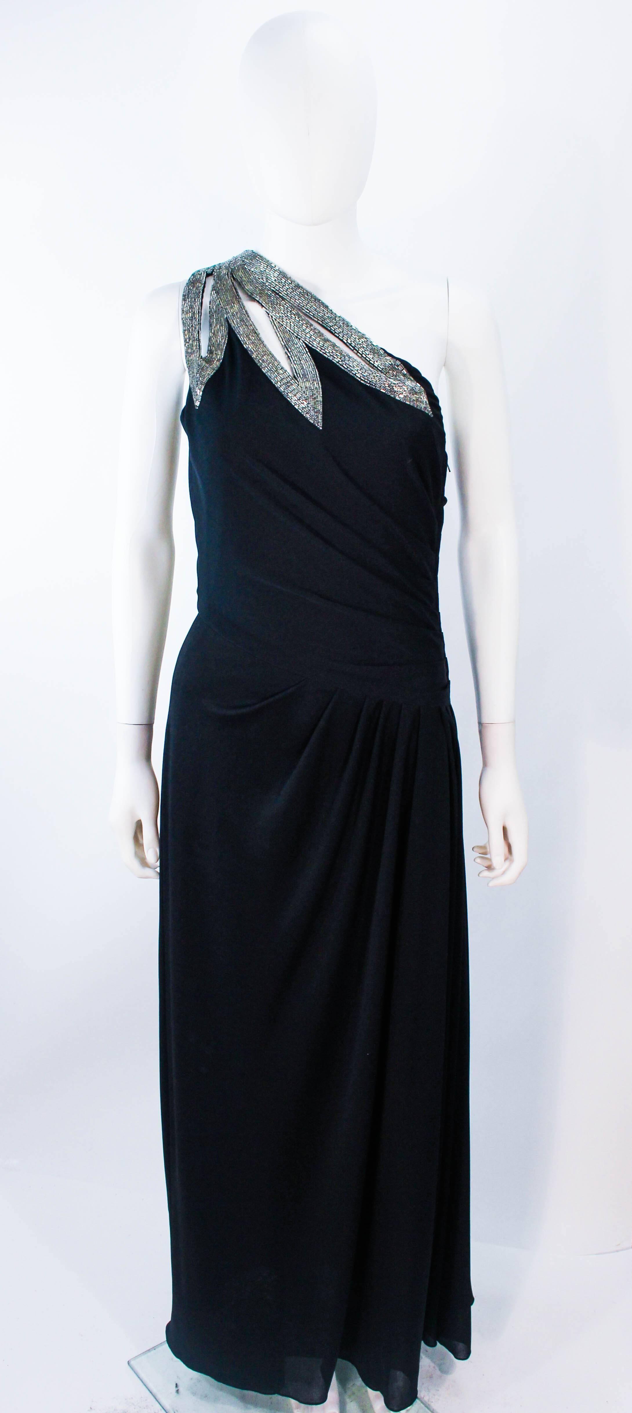 This Travilla gown is composed of a black jersey and features a stunning one shoulder style with beaded applique.  There is a draped design with rouched waist details. There is a zipper closure. Made in USA. 

**Please cross-reference measurements
