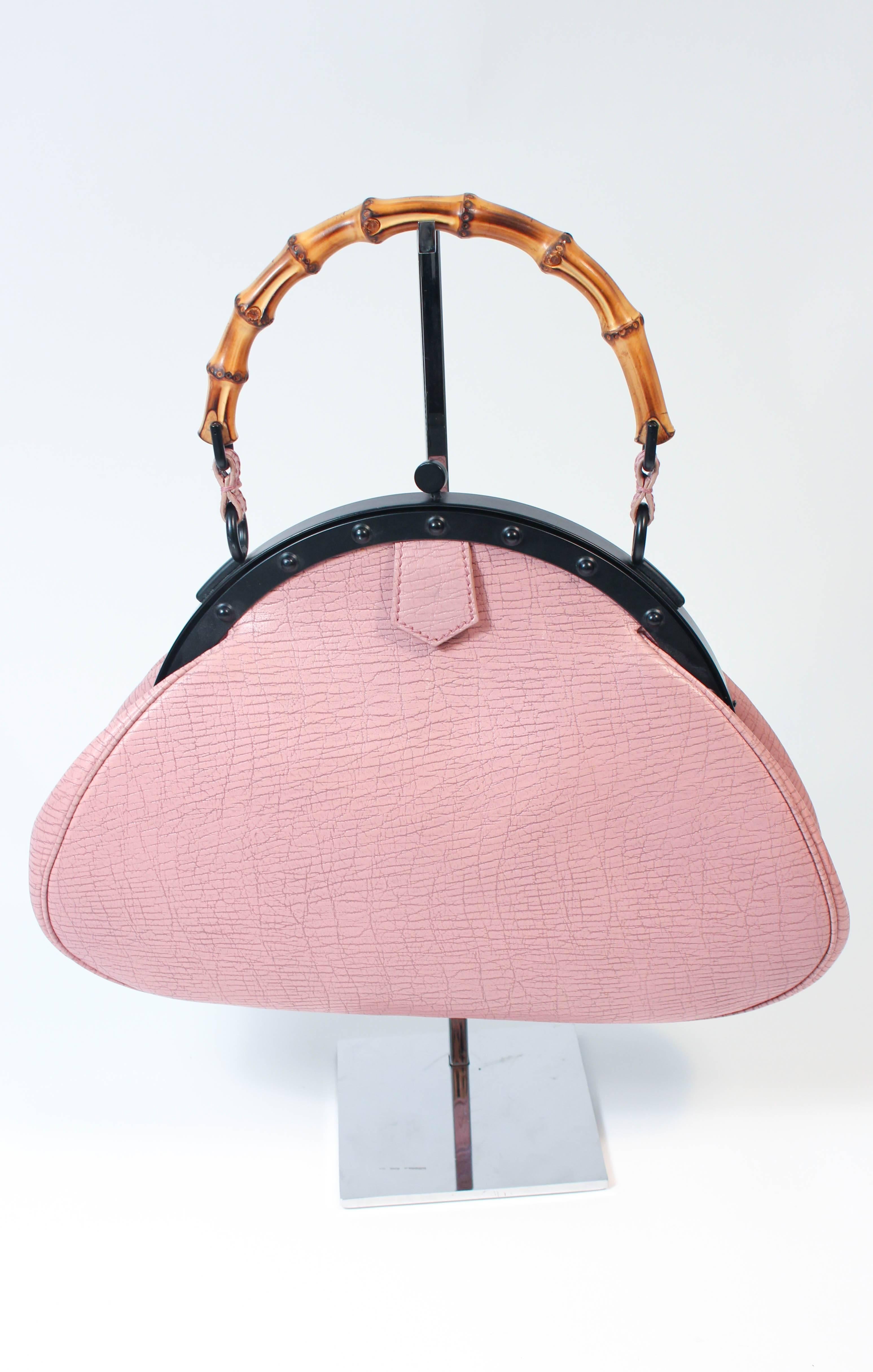 This Gucci purse is composed of a pink mauve leather with a textured pattern. Features a bamboo handle with black frame. There is an interior zipper compartment. In excellent condition comes with dust bag.

**Please cross-reference measurements for