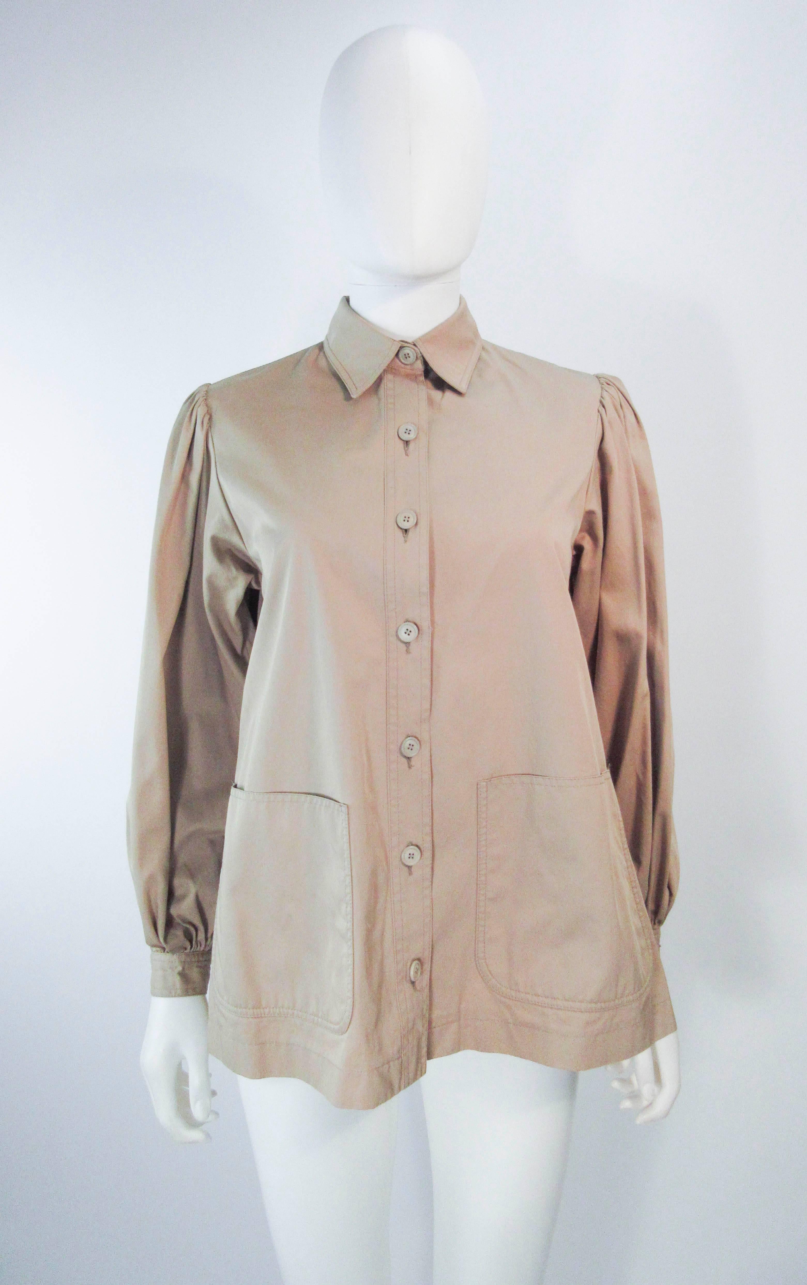 This Yves Saint Laurent top is composed of a khaki fabric & features a utility/safari style. There are center front button closures with front pockets. In great vintage condition there is some signs of wear due to age, the size and fabric content