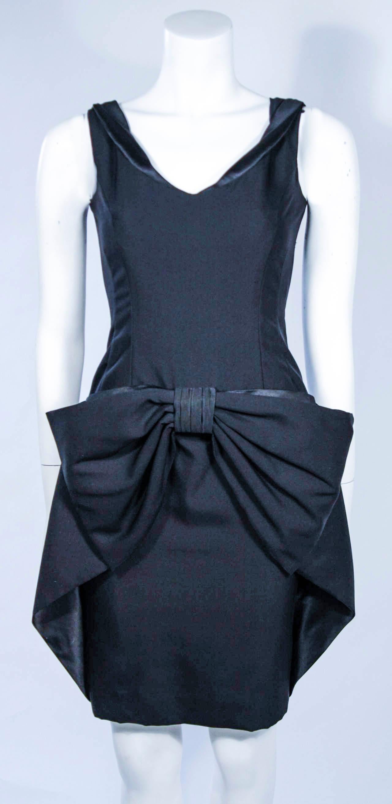 Fashioned from the finest black silk dupioni and accented with silk charmeuse, this sleeveless cocktail features a draped bow concealing pockets.

This is a couture custom order and is available in a variety of fine silks, suitable to your personal