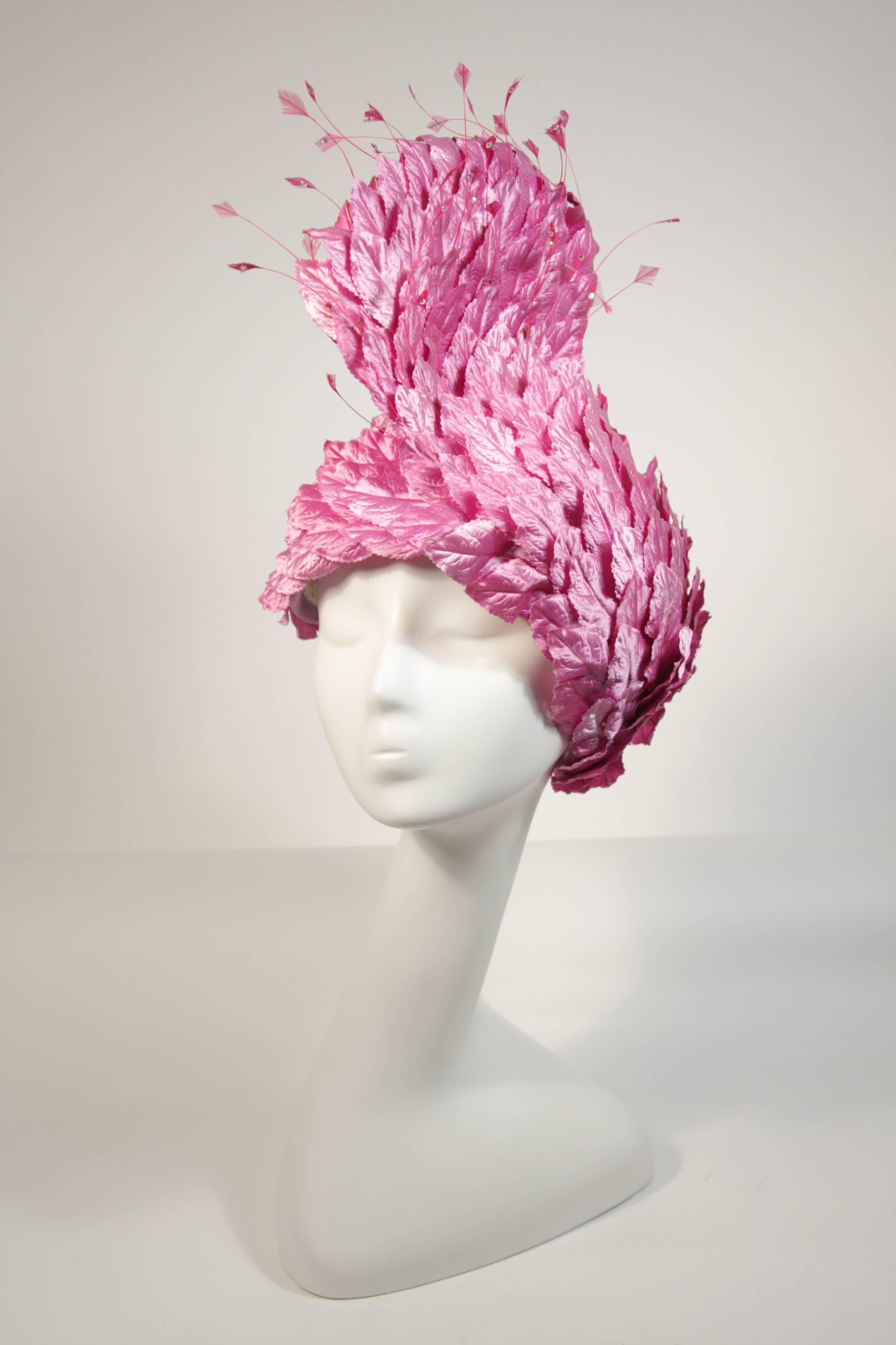 This Jack McConnell hat is composed of pinkish purple leaves in a design reminiscent of feathers, there are feathers at the tip adorned with rhinestones. This is an absolutely beautiful design with amazing fantasy.In excellent condition. Made in