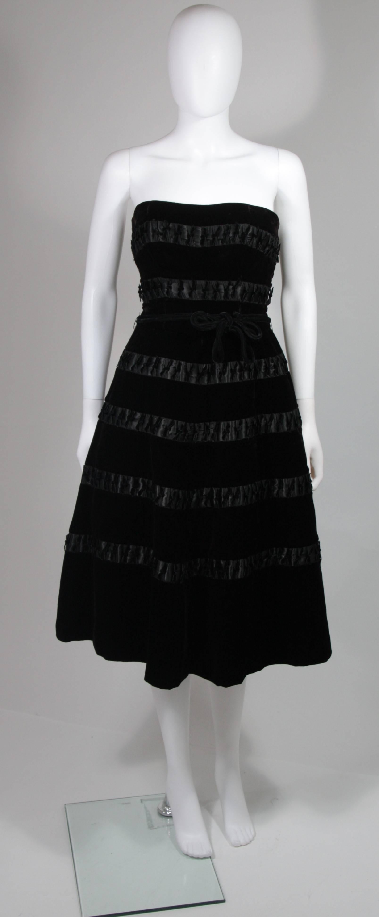This Harvey Berin dress is composed of black velvet with satin accents. The dress features a flare style skirt and ribbon belt. There is a center back zipper closure. In excellent vintage condition. Made in USA.

**Please cross-reference