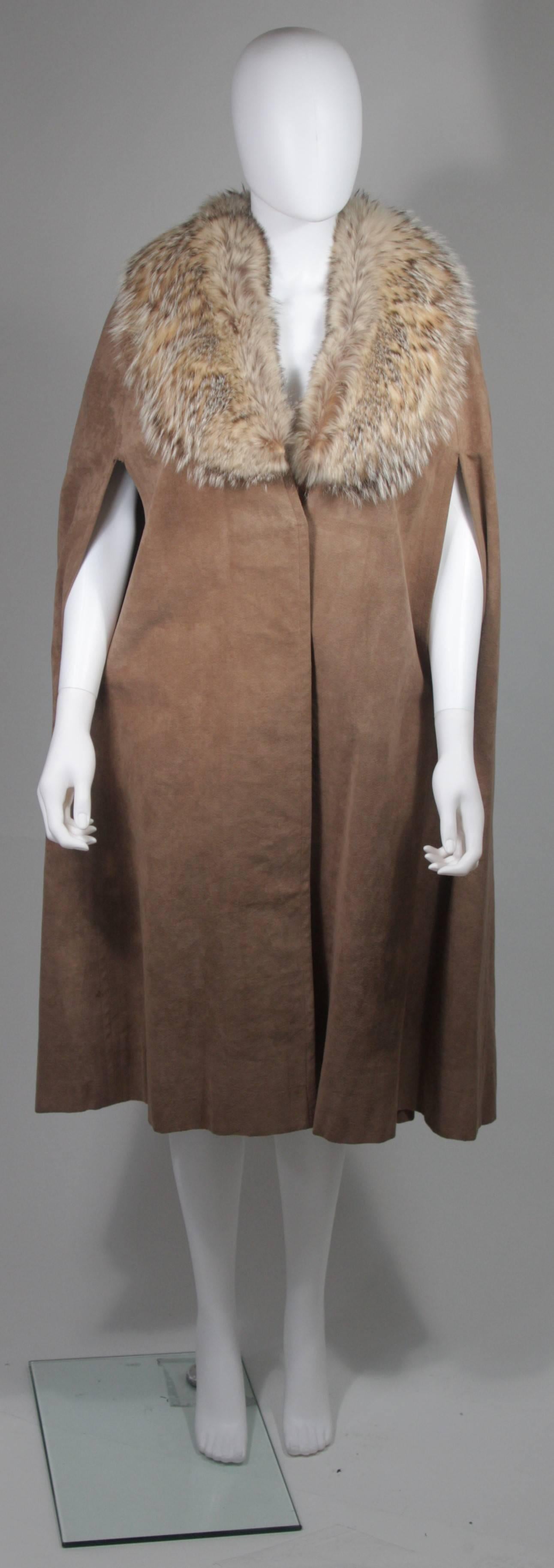 This Nolan Miller cape is composed of a brown suede and features a fox fur collar. There are center front button closures. In excellent condition, lining has slight color variations due to age .  

**Please cross-reference measurements for