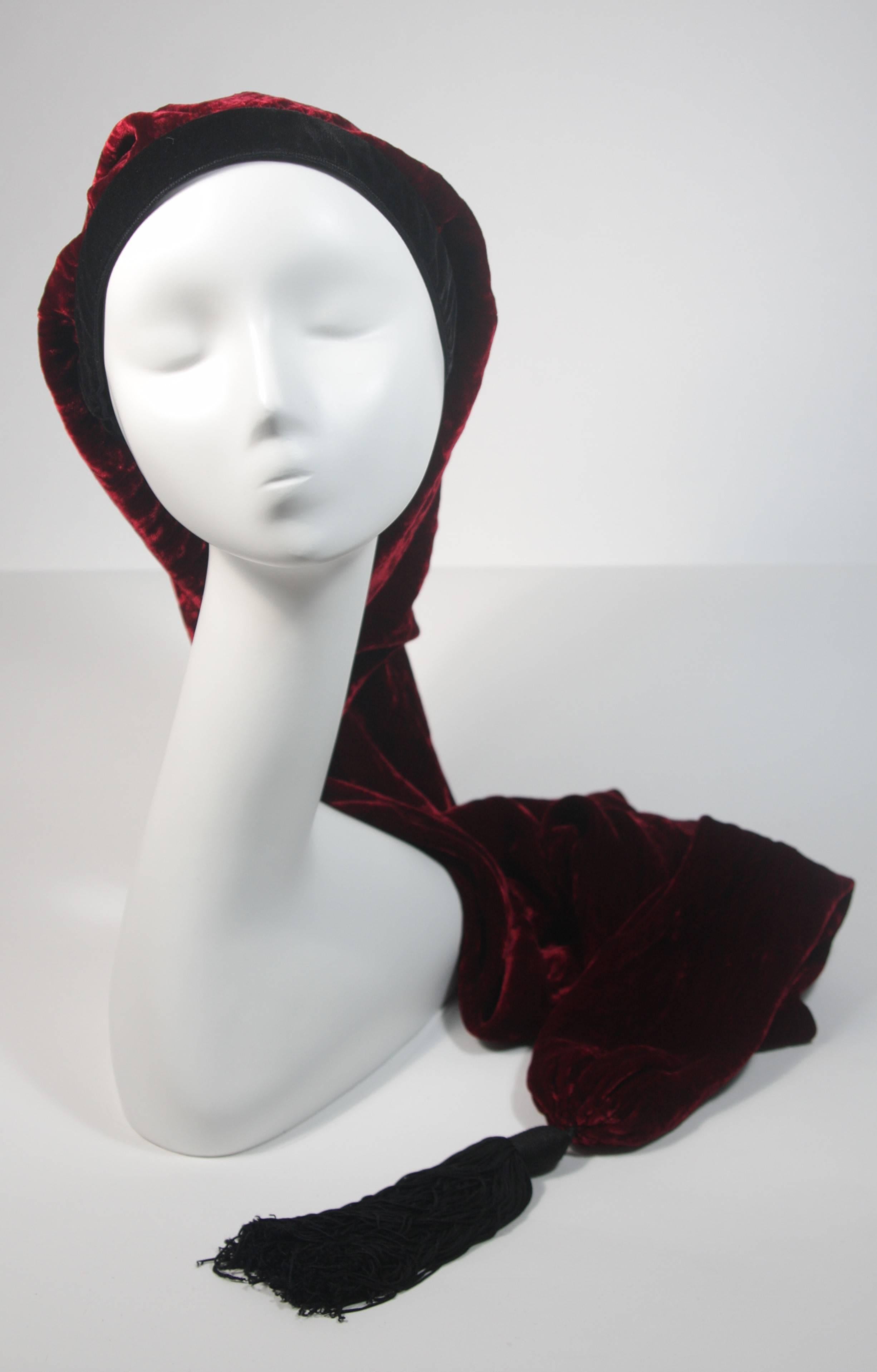 This Yves Saint Laurent Rive Gauche design is available for viewing at our Beverly Hills Boutique. We offer a large selection of evening gowns and luxury garments. 

 This hat is composed of wonderful burgundy velvet and features a tassel.