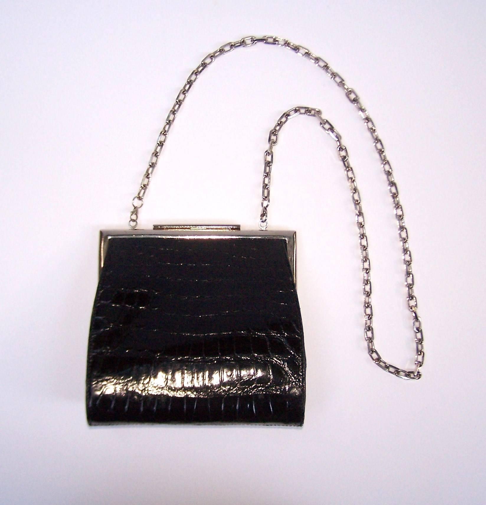This Calvin Klein black alligator handbag can go from a sophisticated biker look to a demure ladylike look all with a change of the shoulder chain.  The bag measures 7.5" across x 2.38" deep x 7.25" tall with gray nubuck interior. 
